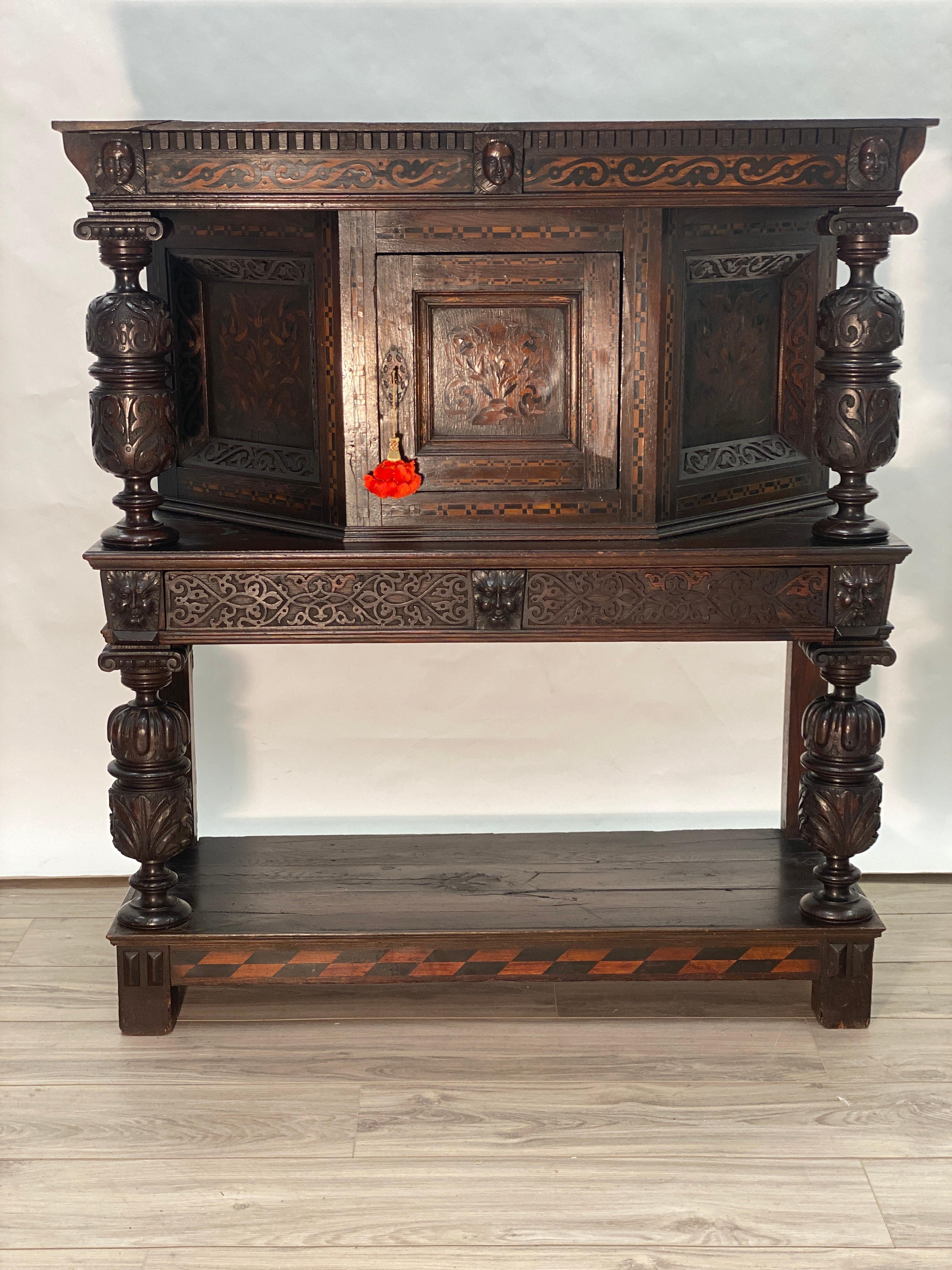 A wonderful early 17th century English Elizabethan Livery cupboard with canted cabinet. Marquetry and Parquetry inlaid on the doors and side panels. Carved bulbous column supports. Carved drawer face on the one center middle drawer. Wonderfully
