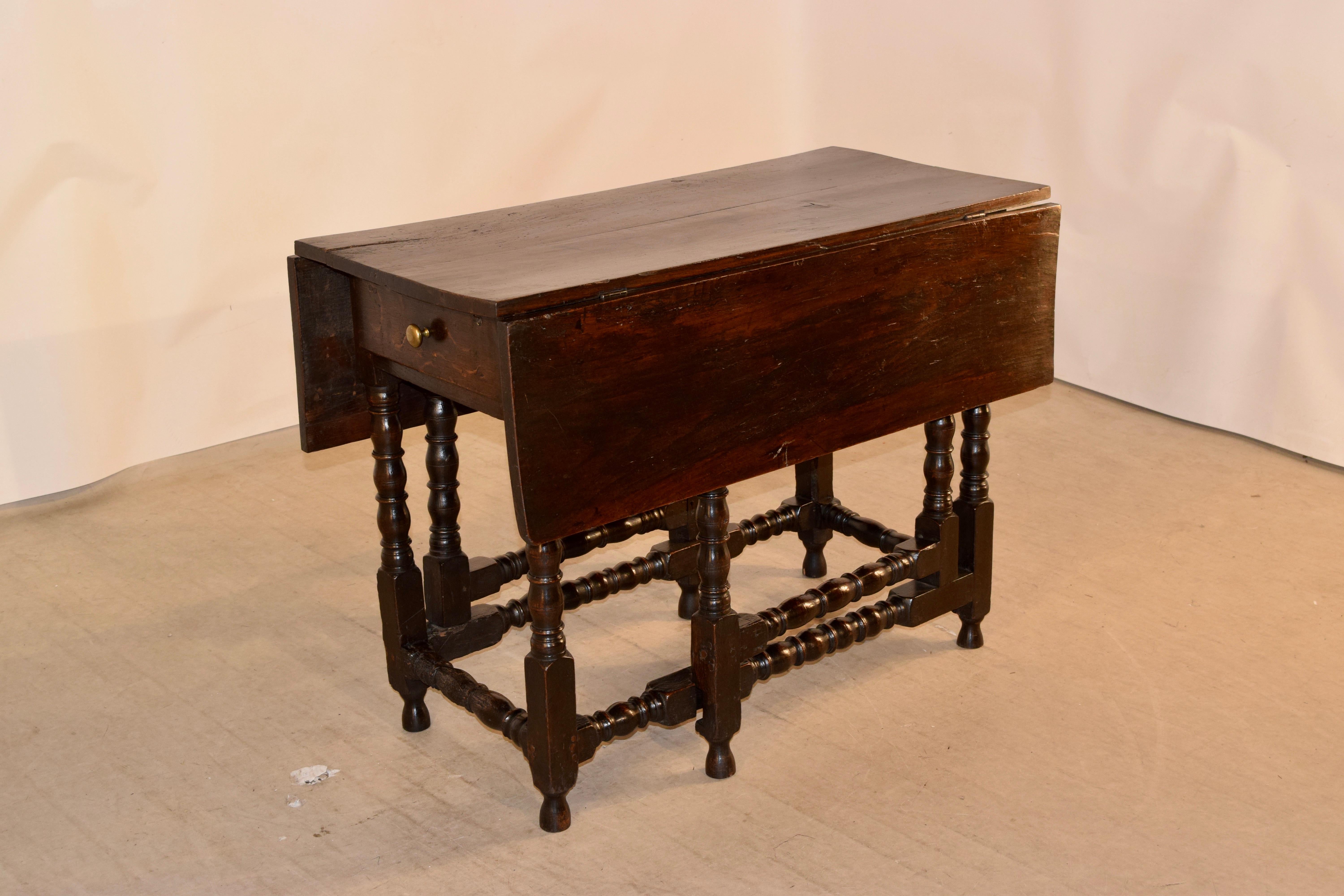 17th century English oak gate leg table with a two board top and two drop leaves, which are made from single boards. The apron contains a single drawer on one end and is supported on hand-turned bob and stop legs joined by matching stretchers. Top