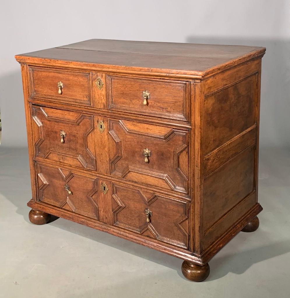 A really super small size late c17th oak geometric chest of drawers with walnut panelled sides and on bun feet. Circa 1685.
( please ignore the bottom left drop handle which is resting at an angle, it rests as it should, but I didn't spot it whilst