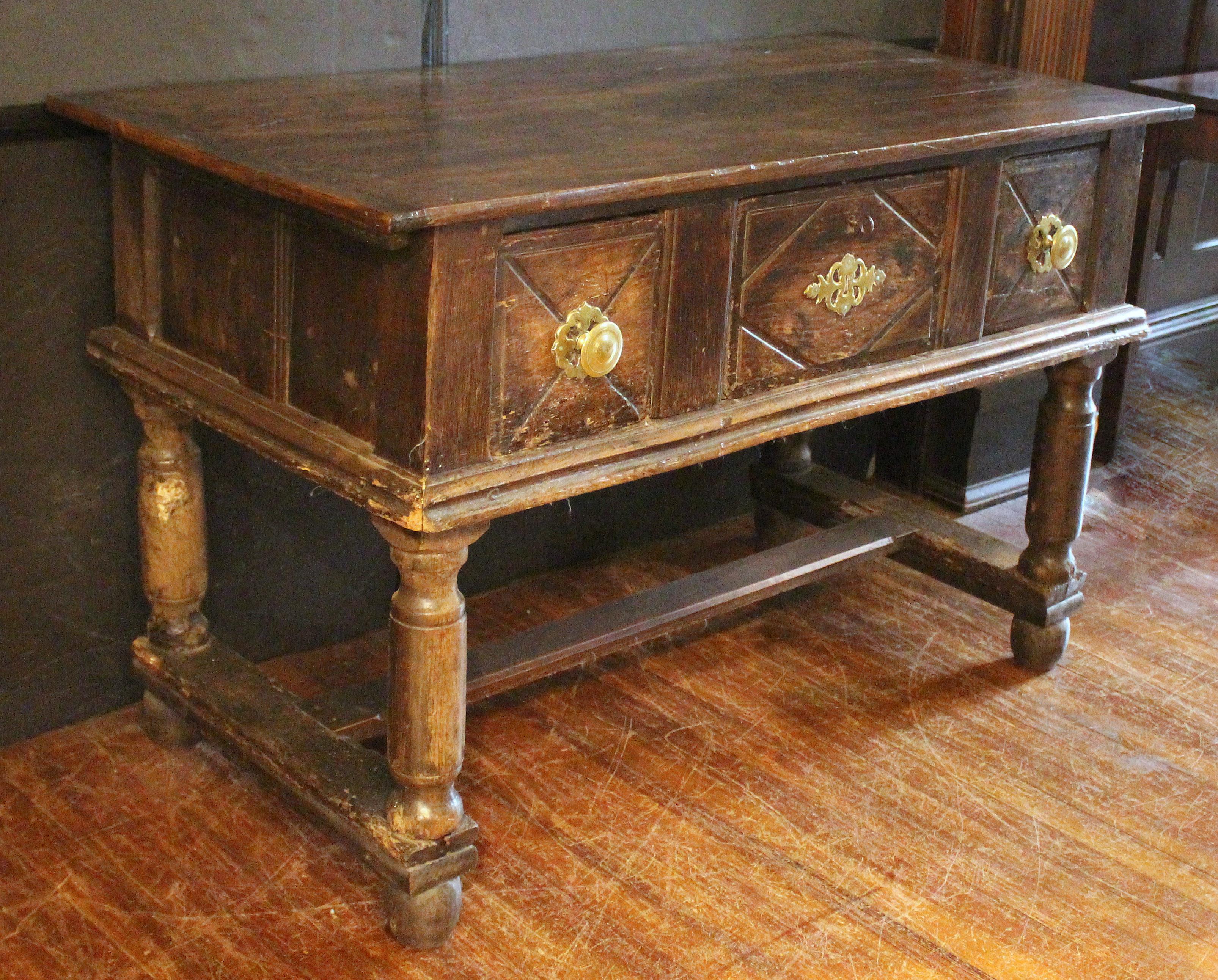 17th century English oak server. Blackened with the patination of centuries. Three drawers, the central with diamond carving & brass cut work plate, the others X carved with brass turned pulls with cut work backplates (hardware is a later addition).