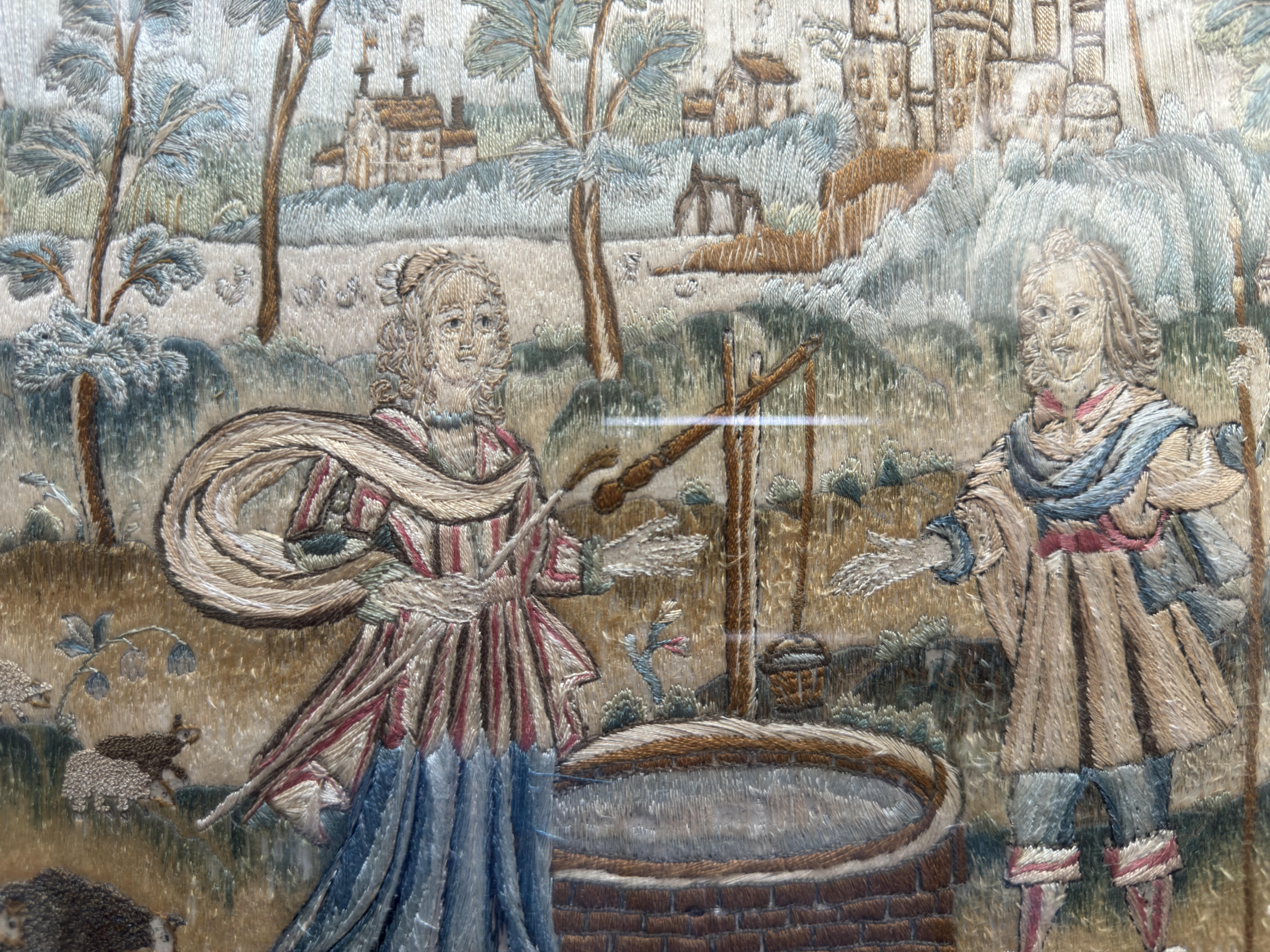 Seventeenth century handstitched silk embroidery of a couple by a well, 11 x 15 inches.