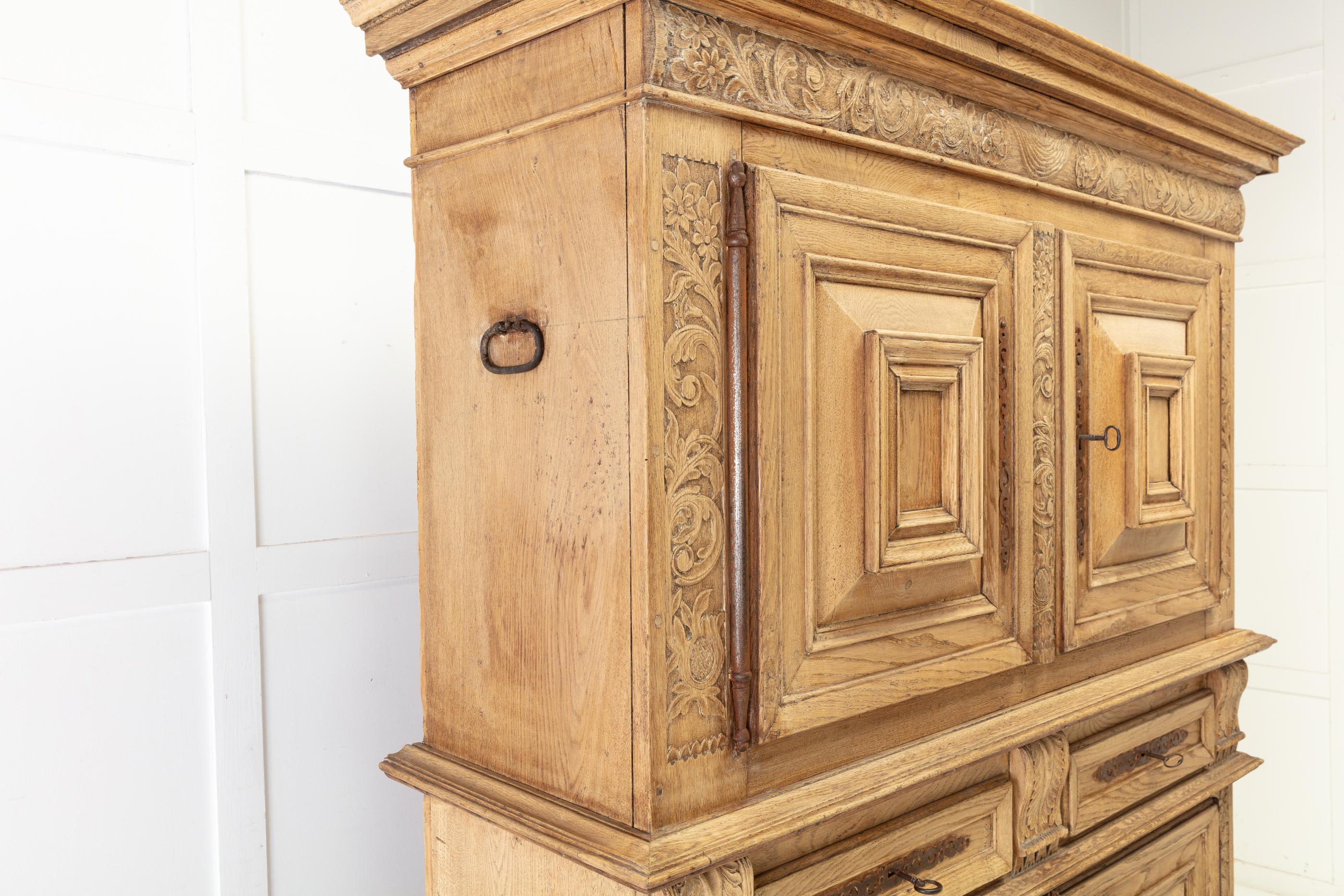 A small and nicely proportioned, 17th century bleached oak, Flemish cabinet. Having two panelled doors at the top and bottom, flanked by attractive carvings of foliage and acanthus leaves. Both sections having one shelf inside. The middle section