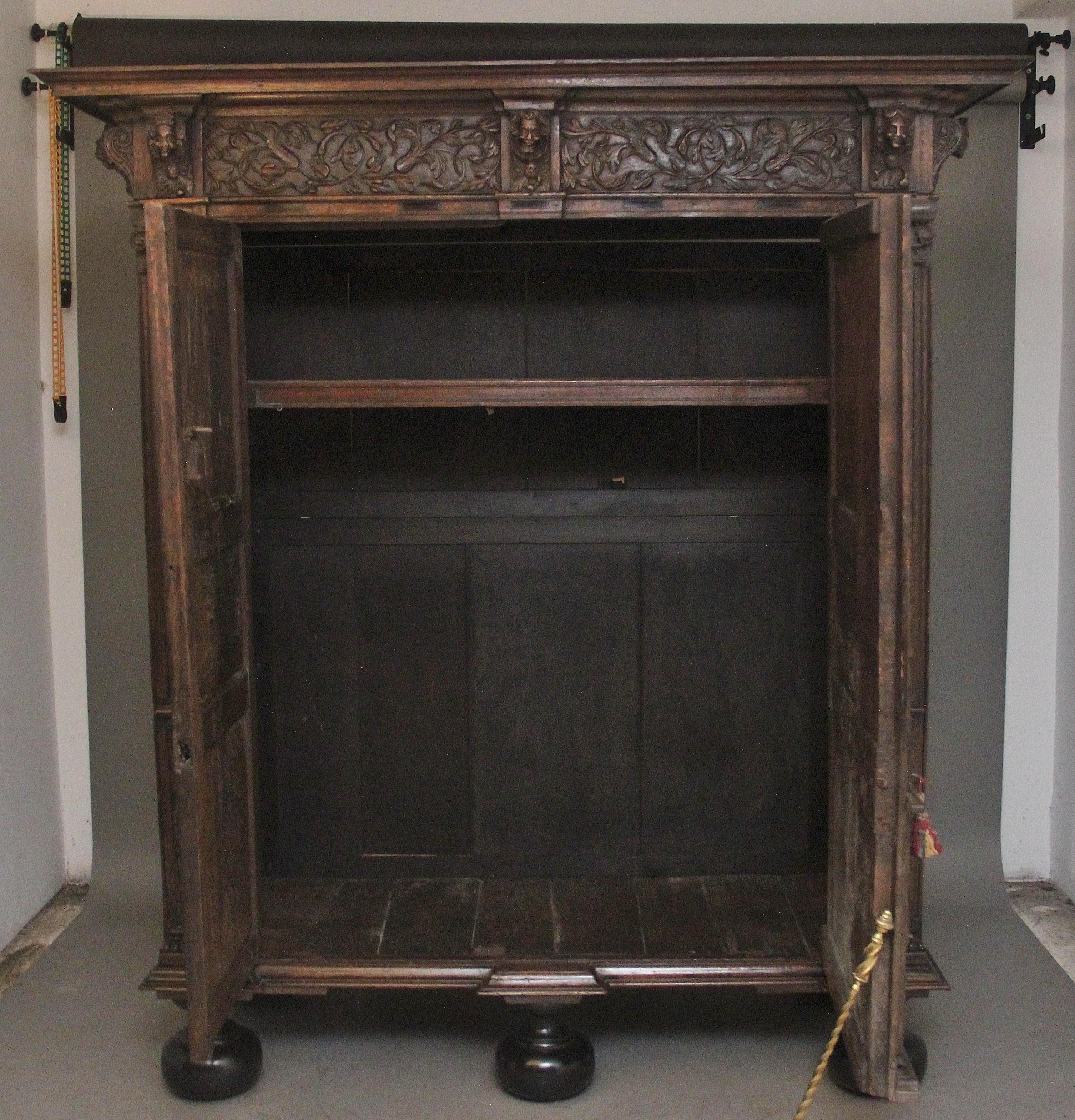 A large and impressive 17th Century Flemish oak cupboard, the moulded cornice above a carved frieze incorporating carved floral decoration and various figure heads, this is at the sides of the cupboard as well as the front, two large doors below