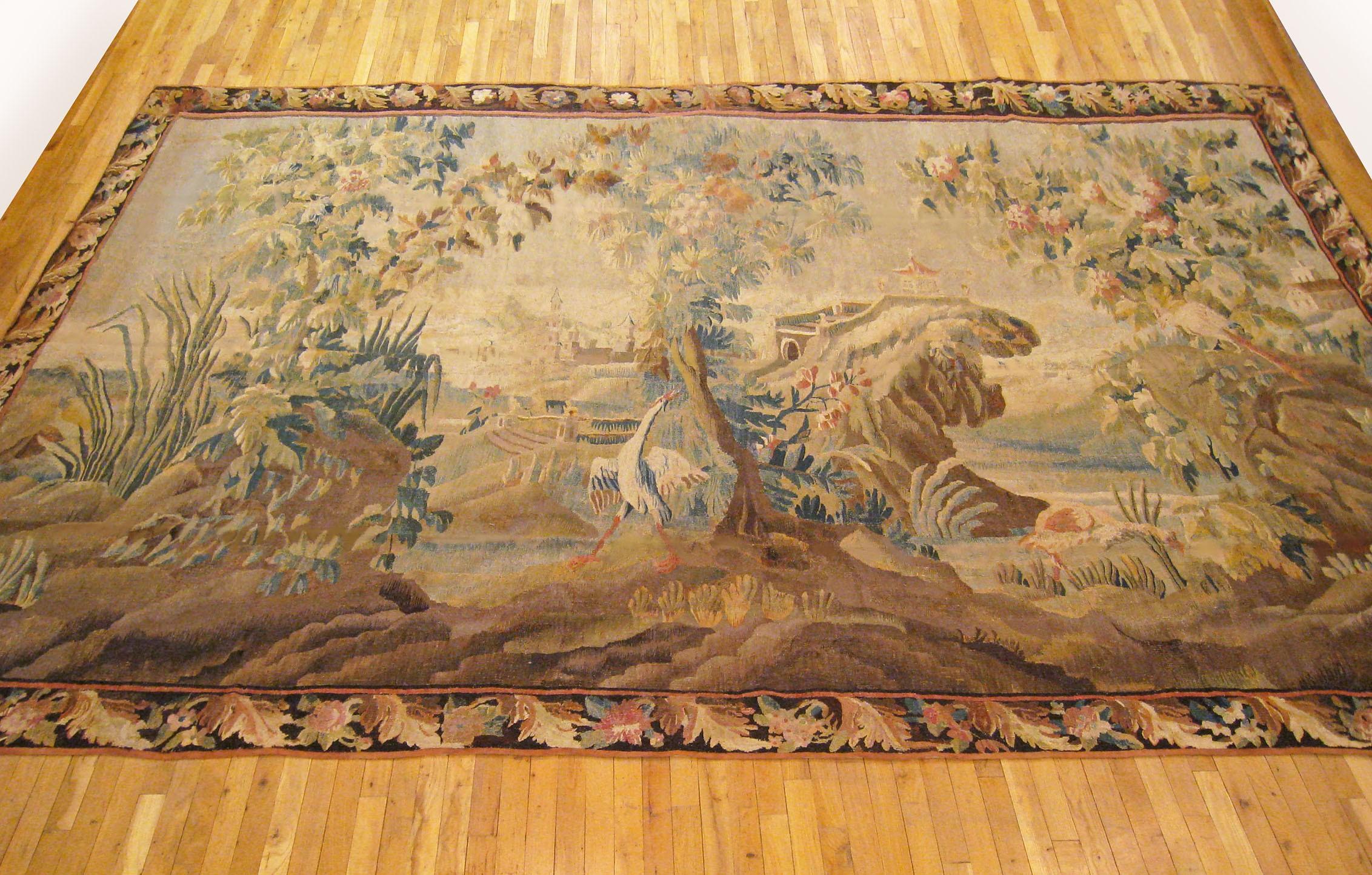 A Flemish chinoiserie landscape tapestry from the 17th century, picturing an idyllic scene with a stately white heron amidst the trees of the verdant foreground, an elegant pagoda overlooking the lake in the middle distance, and a castle amongst the