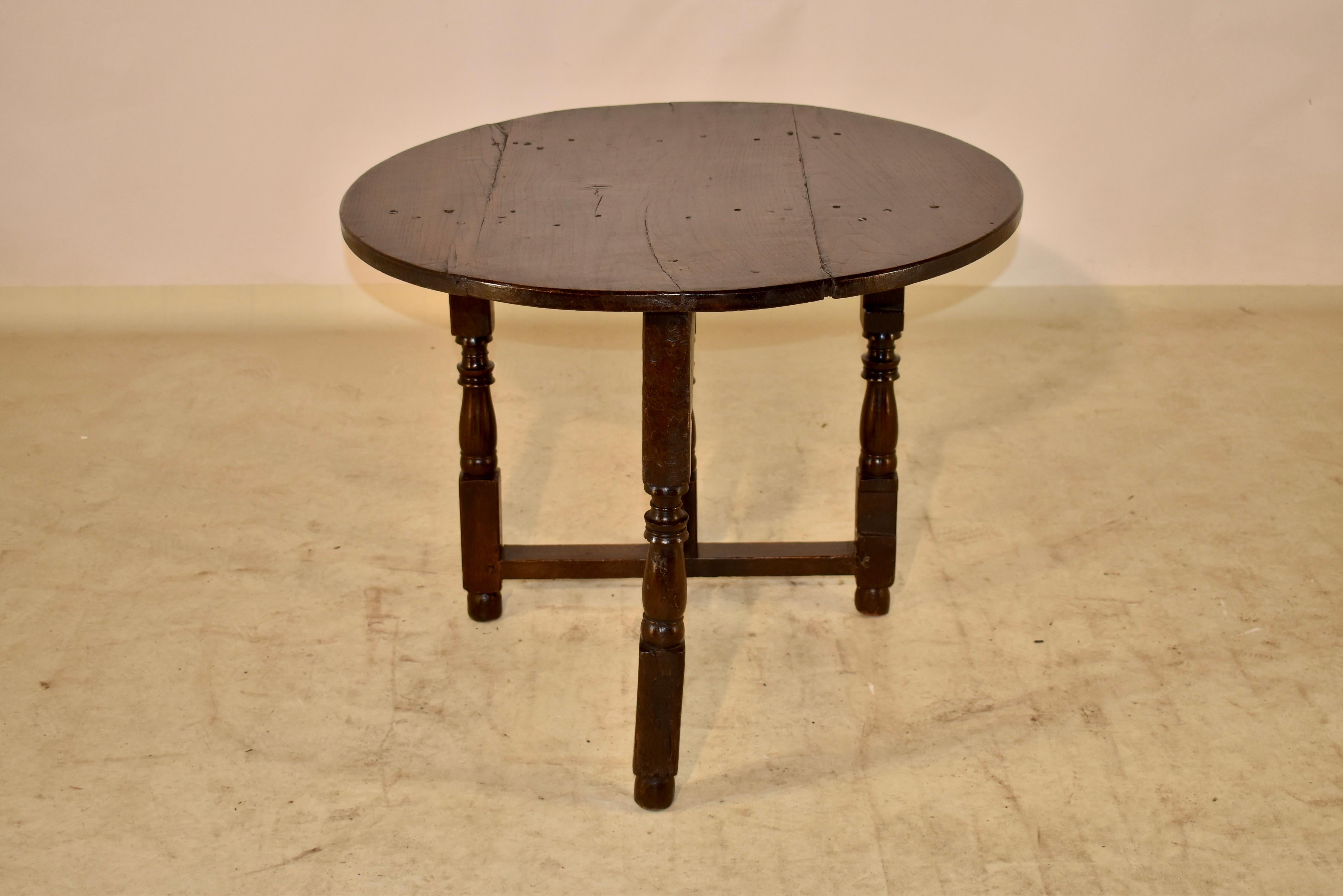 17th Century oak folding table from England with pegged construction on the well worn and patinated top. The top is supported on a base with hand turned legs, joined by simple stretchers and a single gate leg that swings out and allows the table top