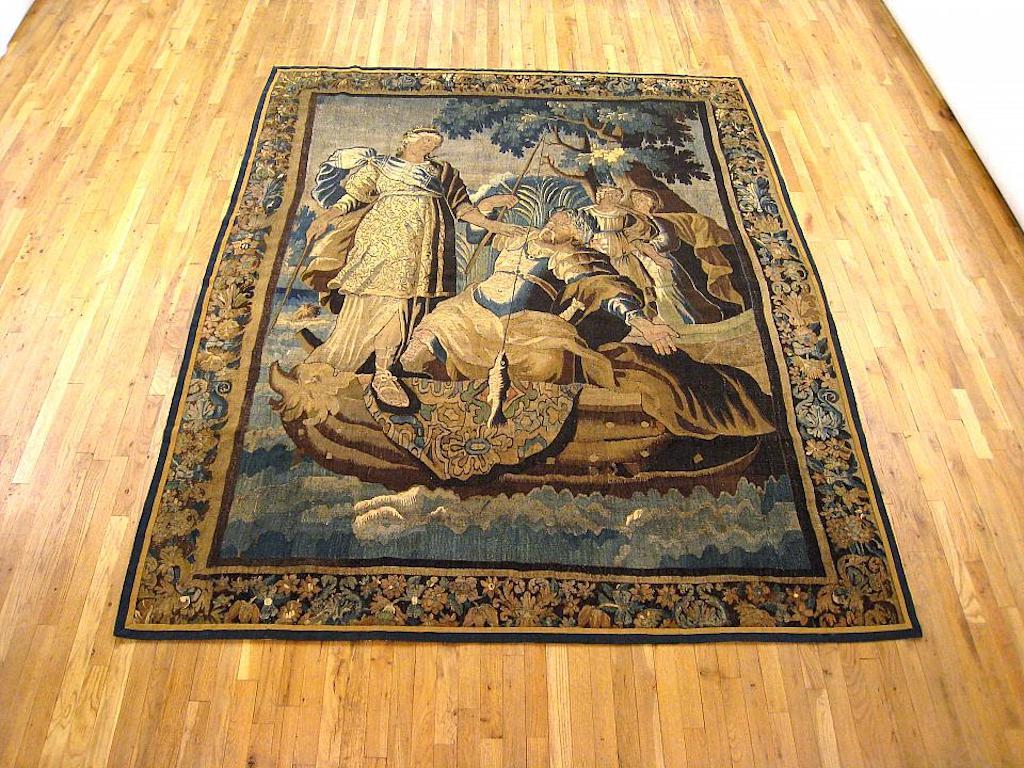 A Franco-Flemish mythological harvest tapestry from the 17th century, featuring the Roman goddess of the hunt, Diana, aiding people who are fishing in the foreground. Enclosed within an elaborate floral border. Wool with silk inlay. Measures: 9’0” H