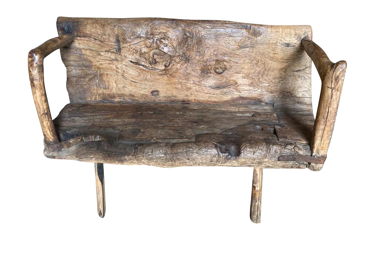 A delightful 17th century Arte Populaire Bench from the Cevennes region of France.  Wonderfully constructed from chestnut with the back and seat being a single piece carved from a trunk with iron strapping.  Fabulous patina and charm.  The seat
