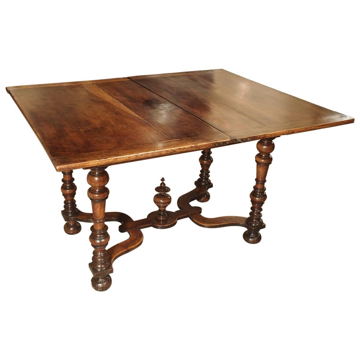 This fascinating French table dates to the early to mid-1600s. It is constructed from walnut and patinated walnut, and has a swivel top that folds open to about 51 x 42 inches. This type of table is referred to as a “table portefeuille”. A plateau