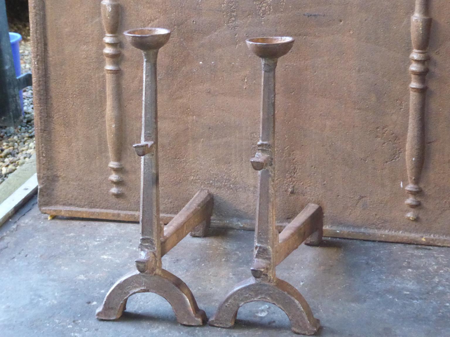17th century French Gothic Andirons made of cast iron. The andirons have spit hooks to grill food and cups to keep drinks warm. This type of andirons is also called cup dogs. The patina of the andirons is brown. Upon request it can be made