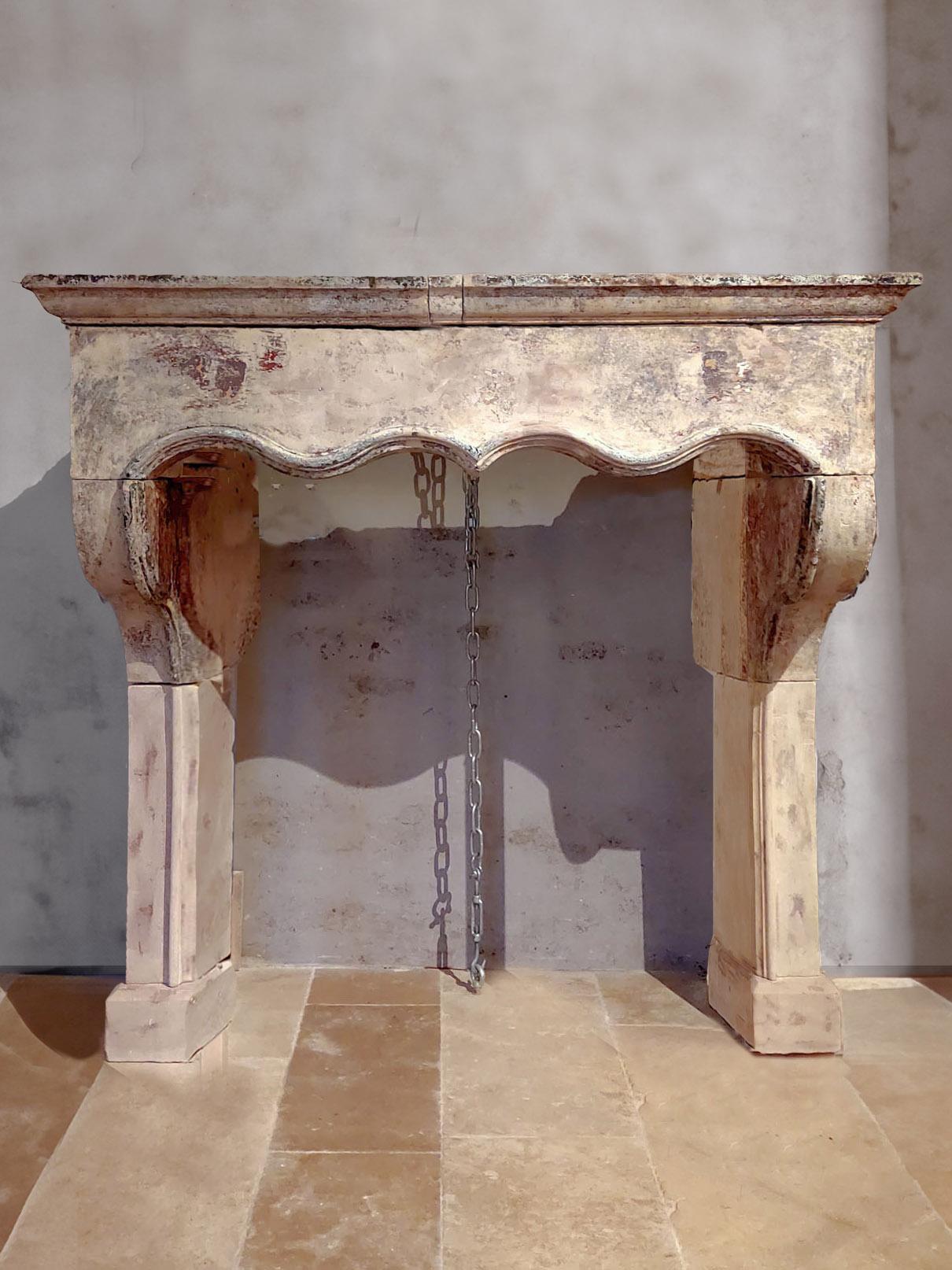 A large 17th century French limestone mantelpiece, showcasing exquisite original paint remains. Crafted in the esteemed Louis Treize style, this antique mantelpiece features a rare acolade front, adding a touch of exclusivity to any room. 

With
