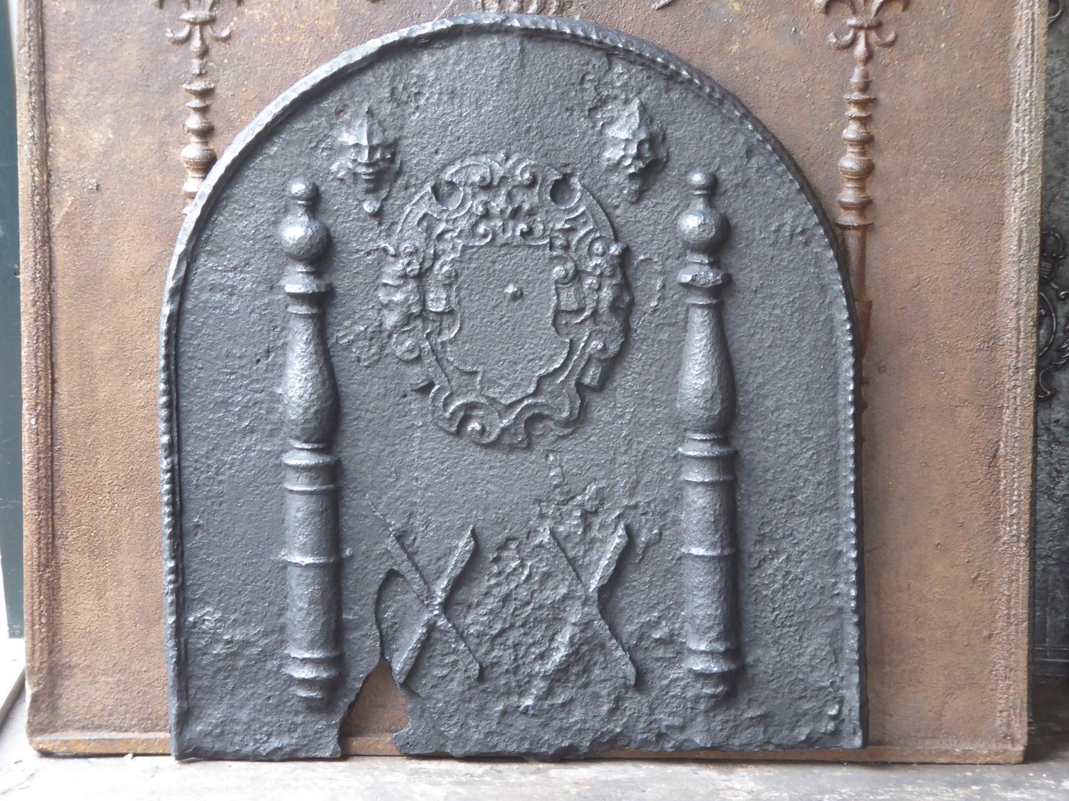 Französischer Louis XIII-Feuerboden aus dem 17. Jahrhundert mit einem Wappen und zwei Herkulessäulen. Die Säulen verweisen auf die Keule des Herkules und symbolisieren Stärke. Die Feuerrückwand ist aus Gusseisen und hat eine schwarze Patina.