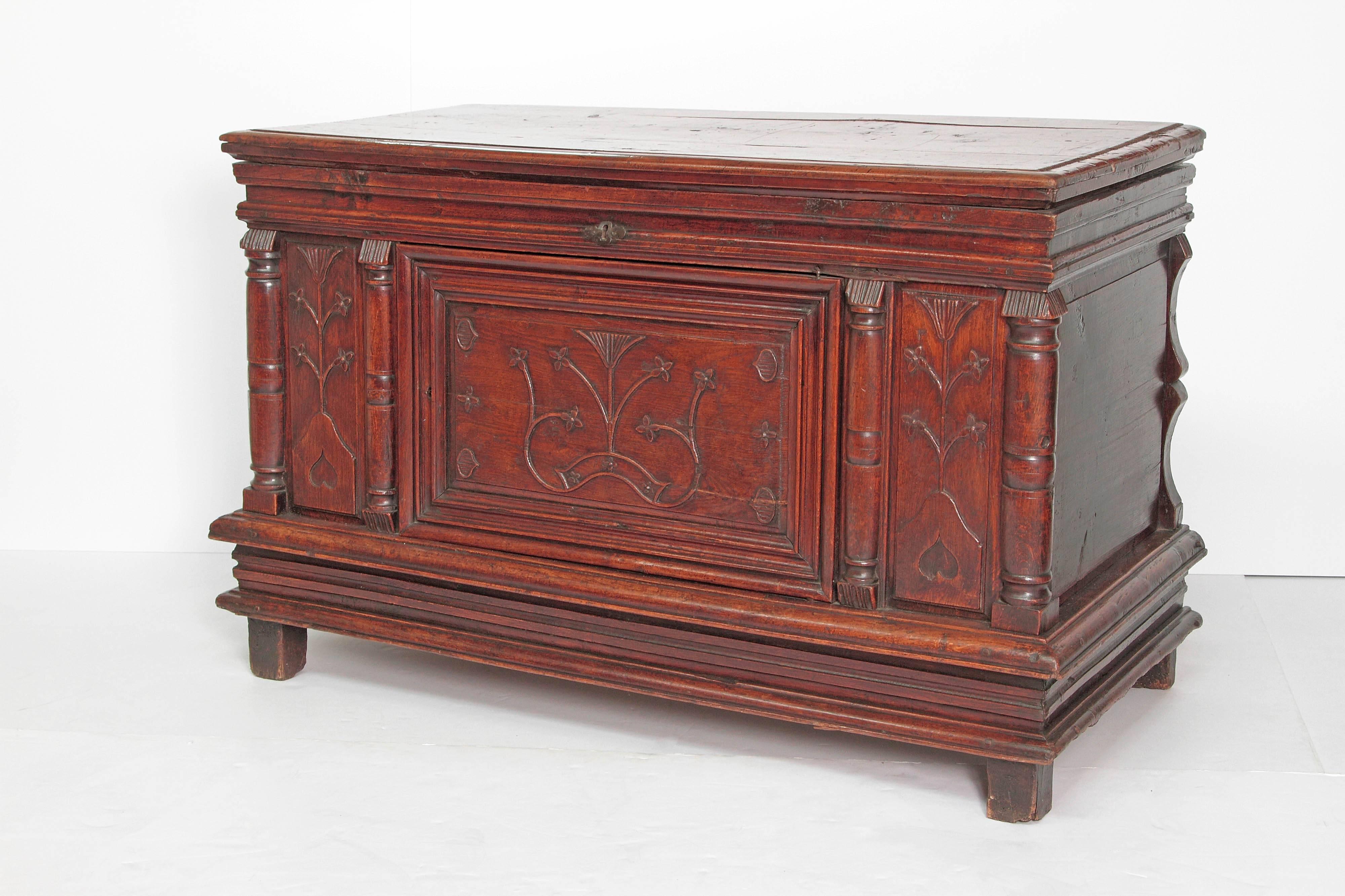 A French Louis XII lift top chest of walnut. Paneled front with stylized thistle floral design with columns framing center door. Stacked block base on feet, circa 1630, France.