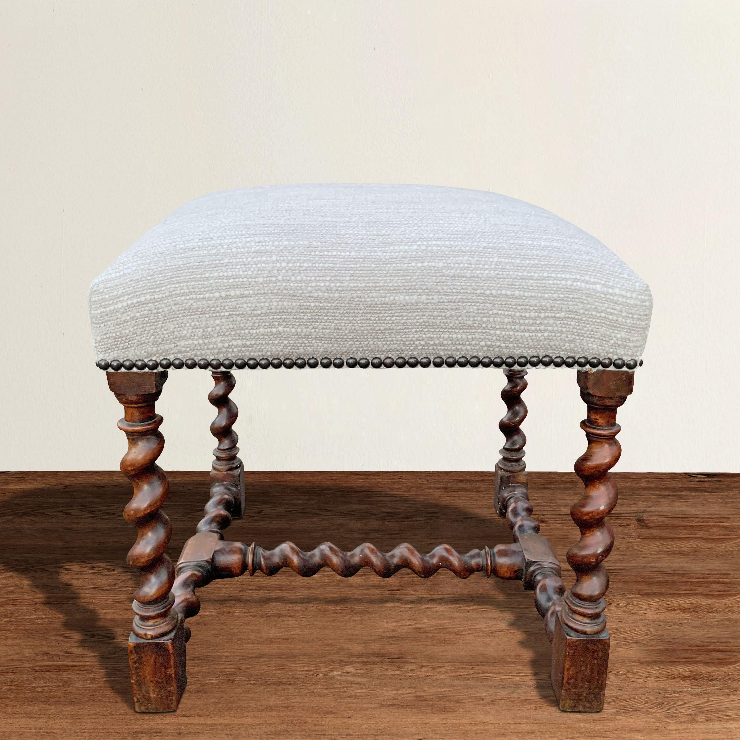 A gorgeous 17th century French Louis XIII walnut stool with barley twist legs and stretchers, and newly upholstered in a wool and linen bouclé. Perfect for tucking under a console table or nightstand, but also functions as a soft side table next to