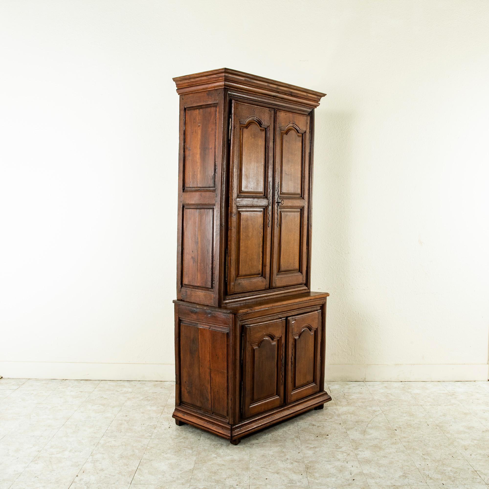 This small scale French Louis XIV period oak buffet deux corps or cabinet from the late seventeenth century is from the region of Normandy and features a narrow width of only 38 inches. Its deep relief hand pegged paneled doors and sides lend