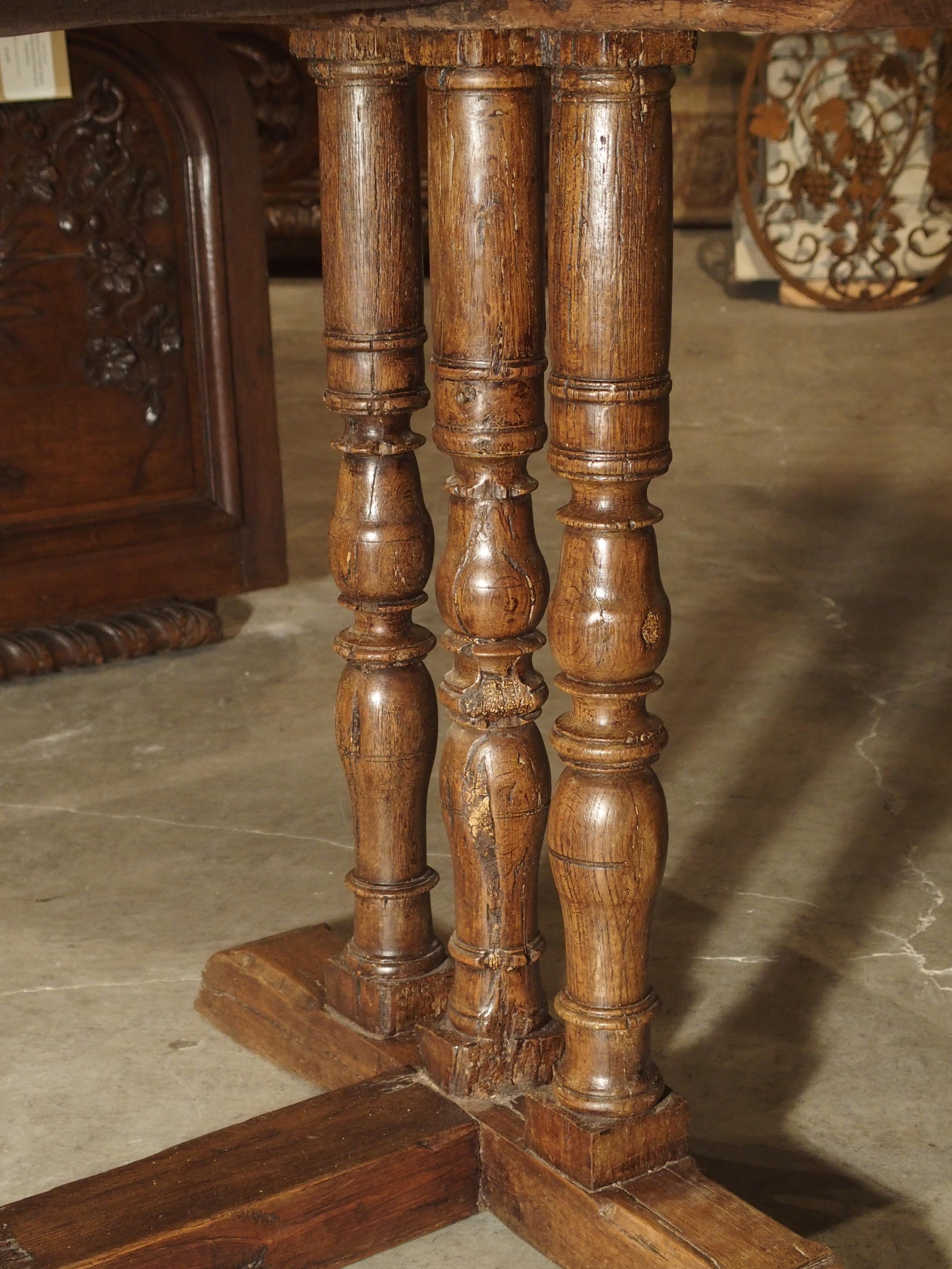 This simple, yet elegant antique table from France dates to the mid to late 1600s (top planks possibly later). The table is solid hand carved oak, and consists of a top made with 4 long vertical planks, supported by a 3 turned balusters at each end.