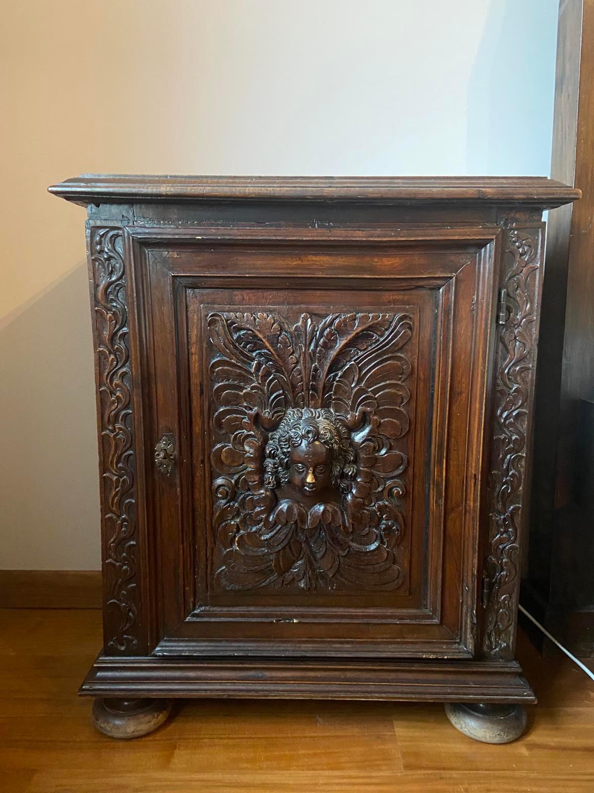 Rectangular support cabinet made of oak opening by a molded door carved with an angel's head in relief in an entourage of foliage scrolls, resting on balls feet.
France, Epoque 17th century
Measures: 85 x 71 x 38 cm.