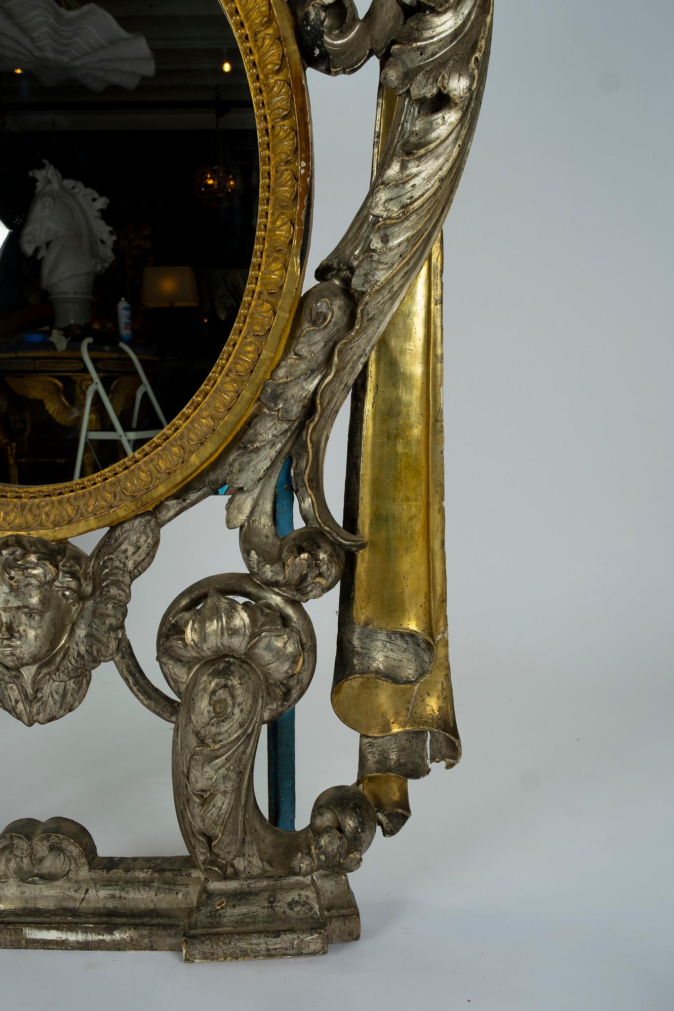 A stunning mirror from the French Renaissance. This period was the cultural and artistic movement in France and is clearly depicted in the hand carved detailing of drapes, scrolling acanthus with religious angel and rays on this silver and gold