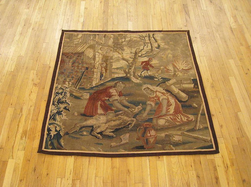 A French rustic hunting tapestry from the 17th century, with a couple catching an elusive boar in the foreground, a cottage in the middle distance at left, and a man tending to a blazing fire in the right distance. Enclosed within a pair of narrow