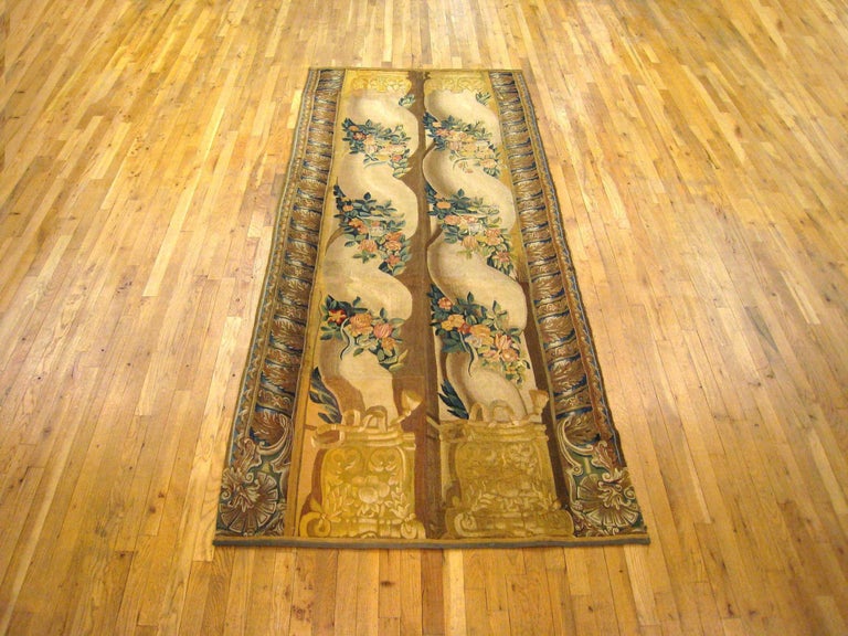 A French architectural tapestry panel, featuring a pair of regal spiral columns, with elaborate bases at top and bottom, and ringed with floral garlands. Encased by sturdy yet elegant spiral borders on either side. Wool with silk inlay. Measures: