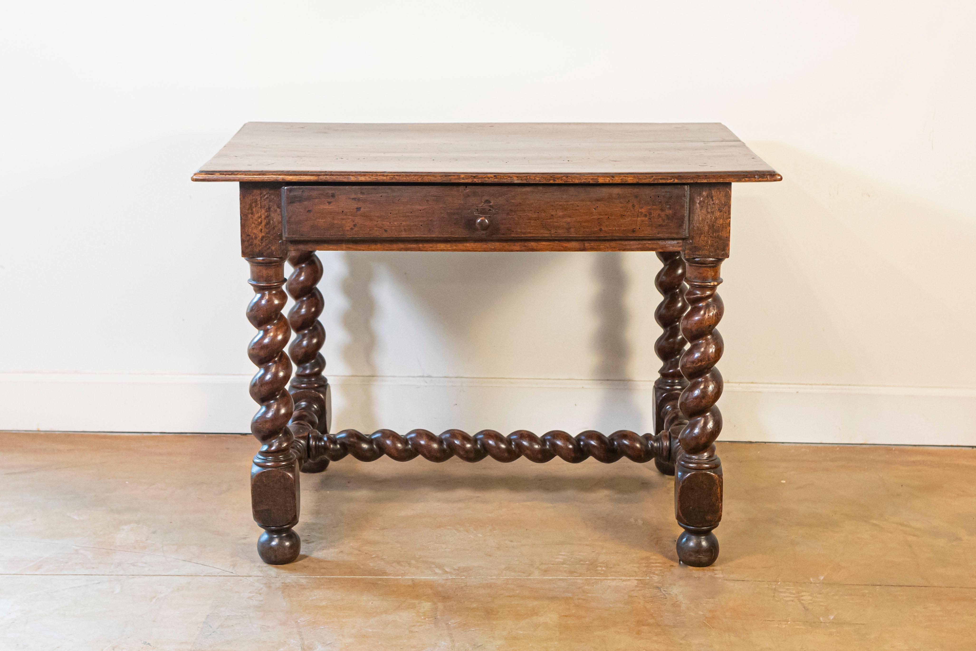 A French 17th century period Louis XIII walnut side table with single drawer and barley-twist base. This French side table features a rectangular planked top with rounded edges sitting above a simple apron comprising a single long drawer, opening