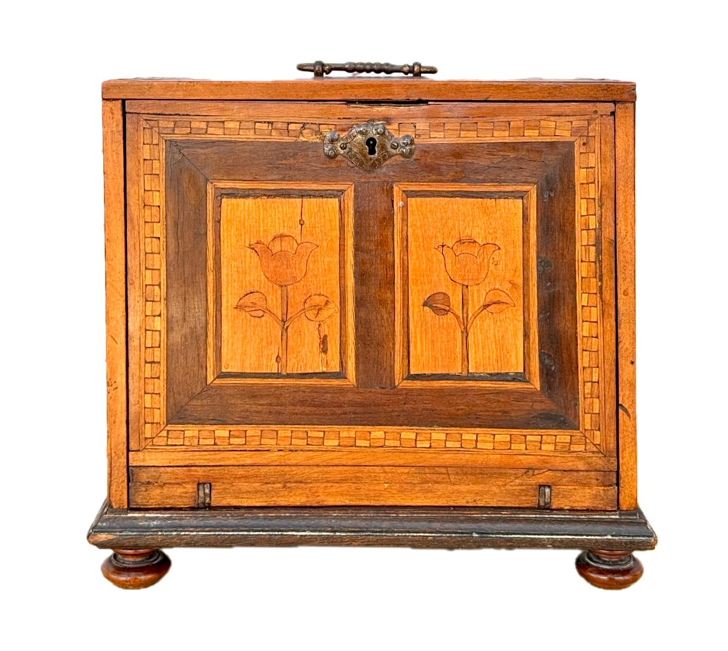 Mobile da tavolo tedesco intarsiato del XVII secolo. Il mobile è finemente lavorato con intarsi che presentano un disegno floreale su un'unica anta esterna. L'interno è dotato di cassetti e armadi intarsiati con scene architettoniche. Venivano