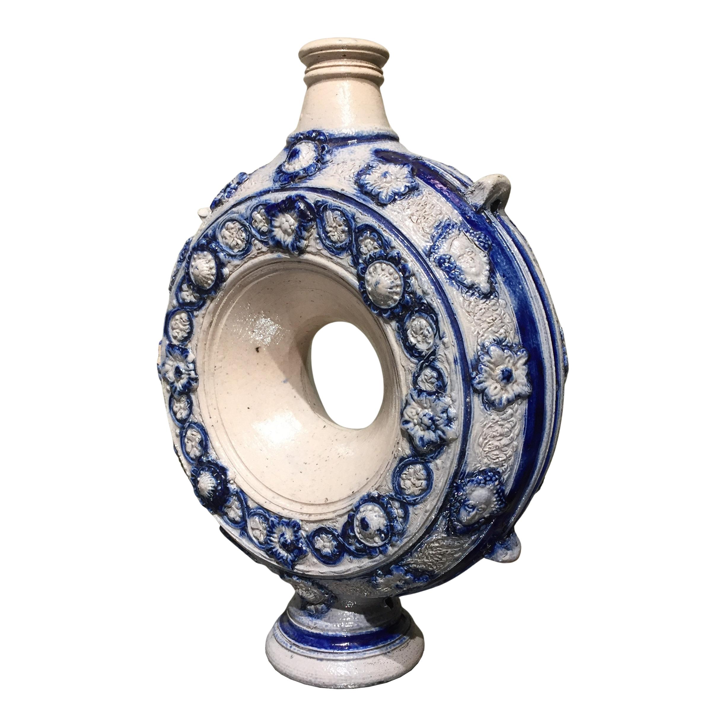 Germany
Westerwald
First half of the 17th century

A beautiful German Westerwald Ring jug, Ring krüg, or pilgrim bottle. 
The grey body is wonderfully decoration in relief with bands of flowers and masks highlighted with blue. 
At the sides and in