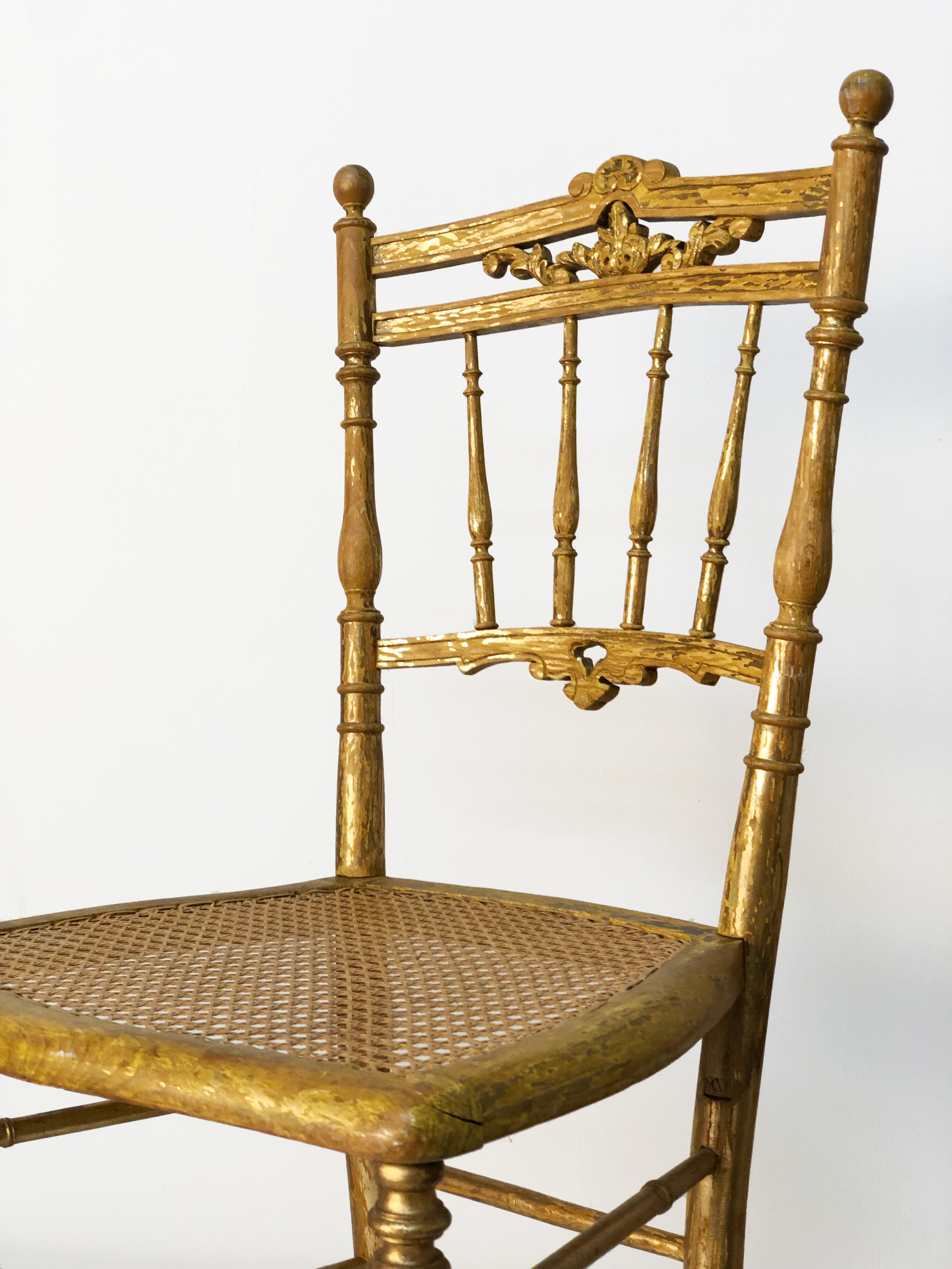 Offered for your consideration are a pair of antique Italian 17th century gilded Empire Chiavari chairs. Gilded willow hardwood with woven cane seat. Hand-carved ornamentation to top rail. Lathed legs, spindles and stretchers. Heavy losses to