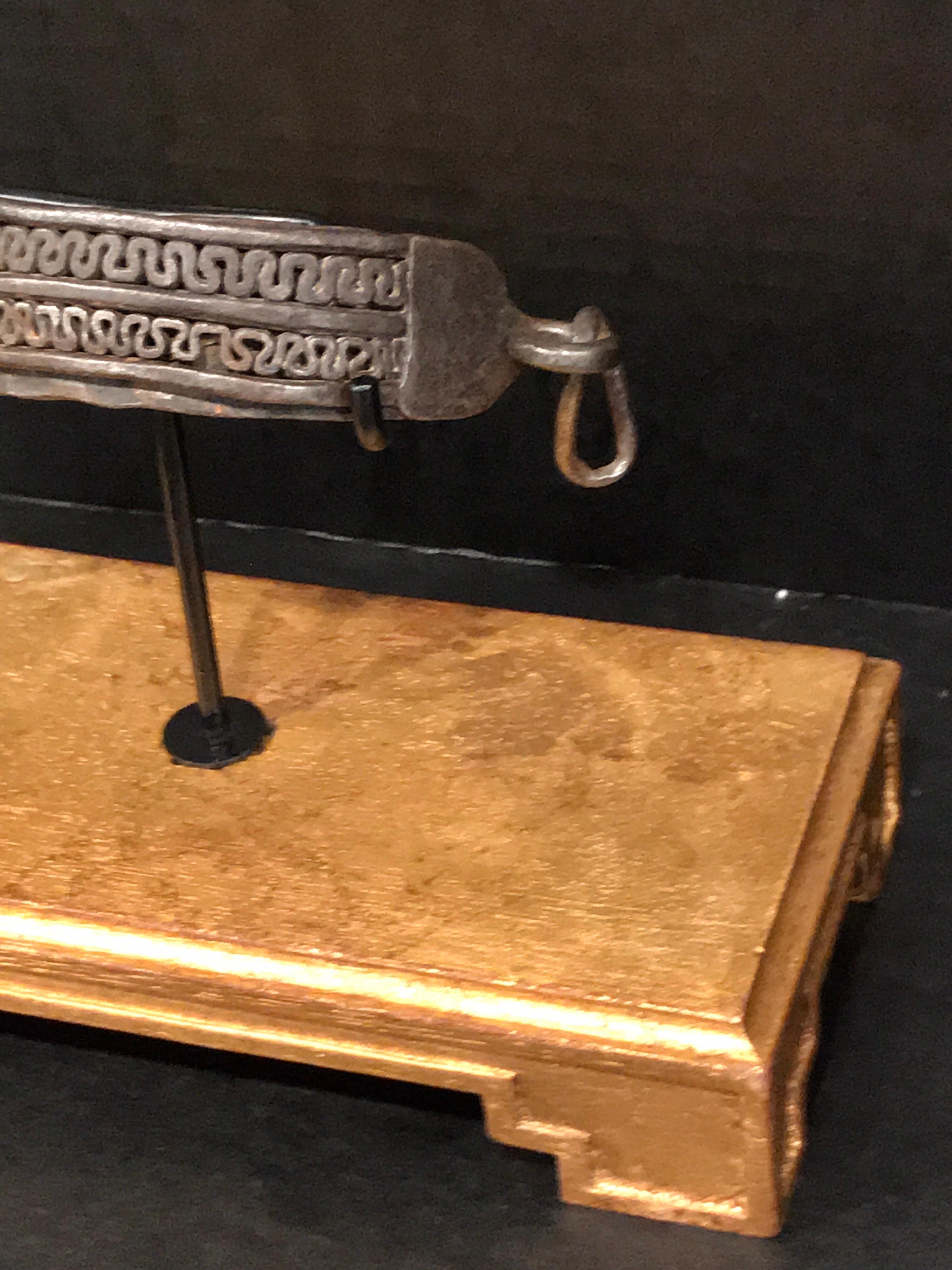 Eisernes Hundehalsband aus dem 17. Jahrhundert, museal auf einem rechteckigen Sockel aus Vergoldungsholz montiert. Mit zwei Reihen neoklassizistischer Beschläge. Das 6
