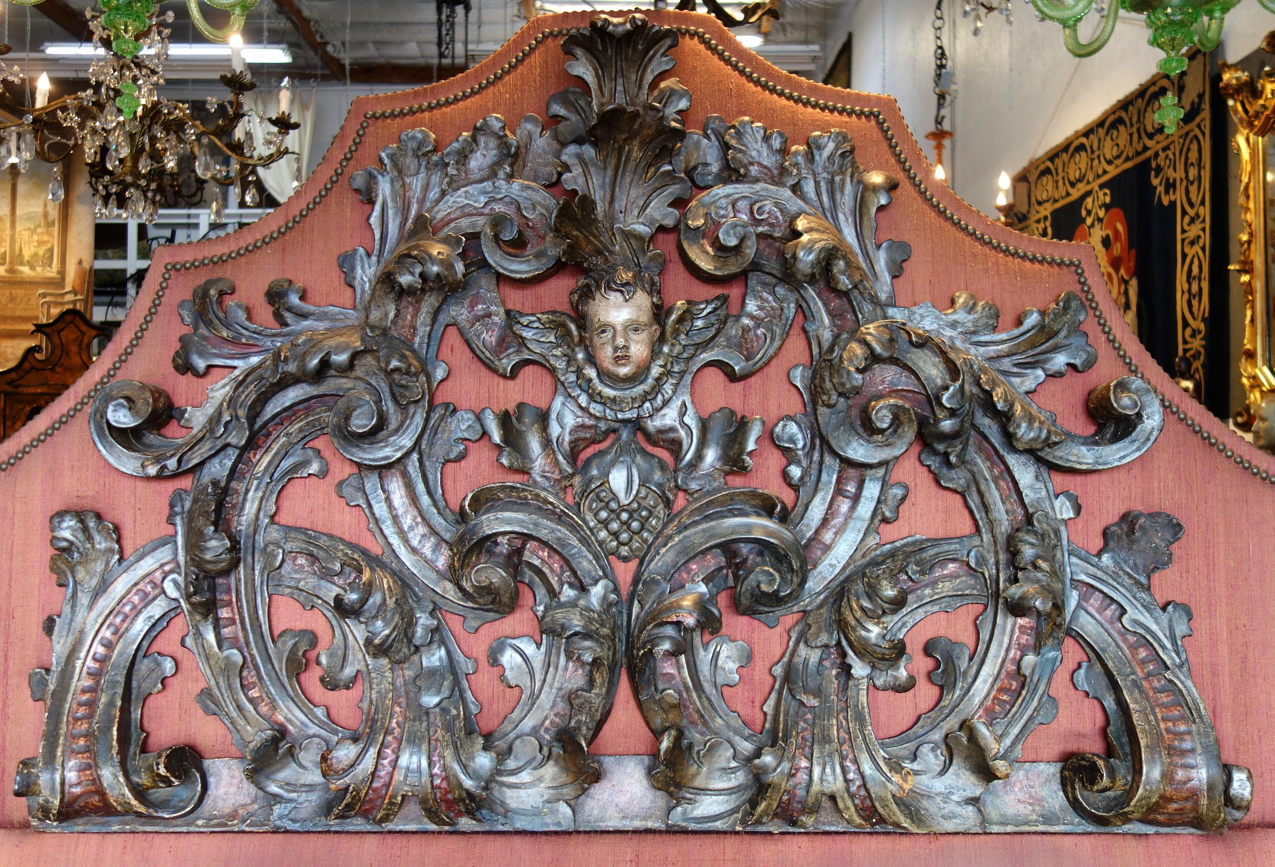 Late 17th century Italian Baroque lintel carved in triangular shape with acanthus scrolls, centered by a winged cherub face. Polychrome painted. Superb Italian craftsmanship. Previously refinished. Currently mounted to an upholstered headboard
