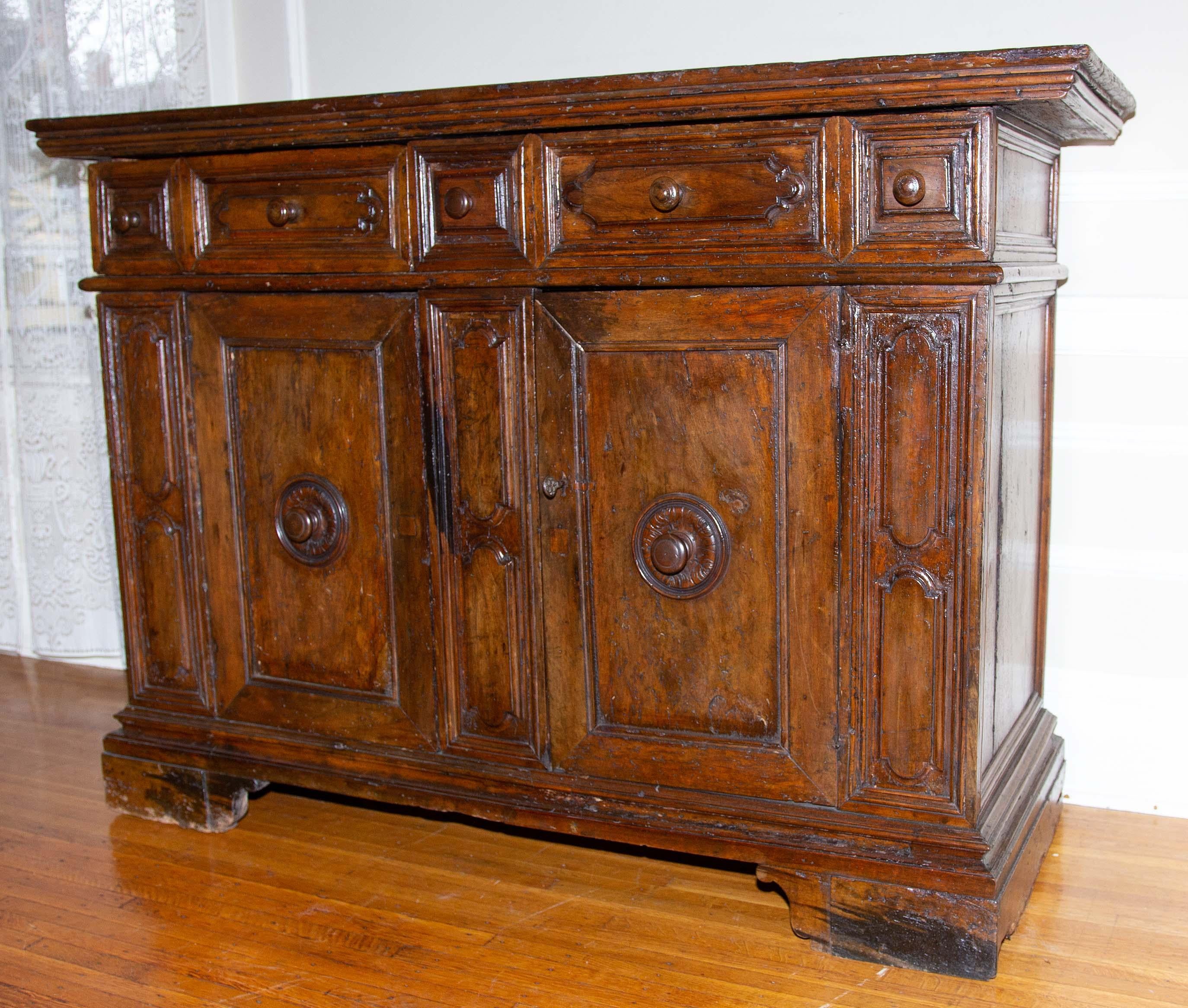 Baroque 17th century Italian hand carved walnut credenza. Two drawers over two doors. Very old, and probably the original finish. Rich walnut color. From the Tuscan area of Italy. Minor old repairs. Beautiful antique condition.