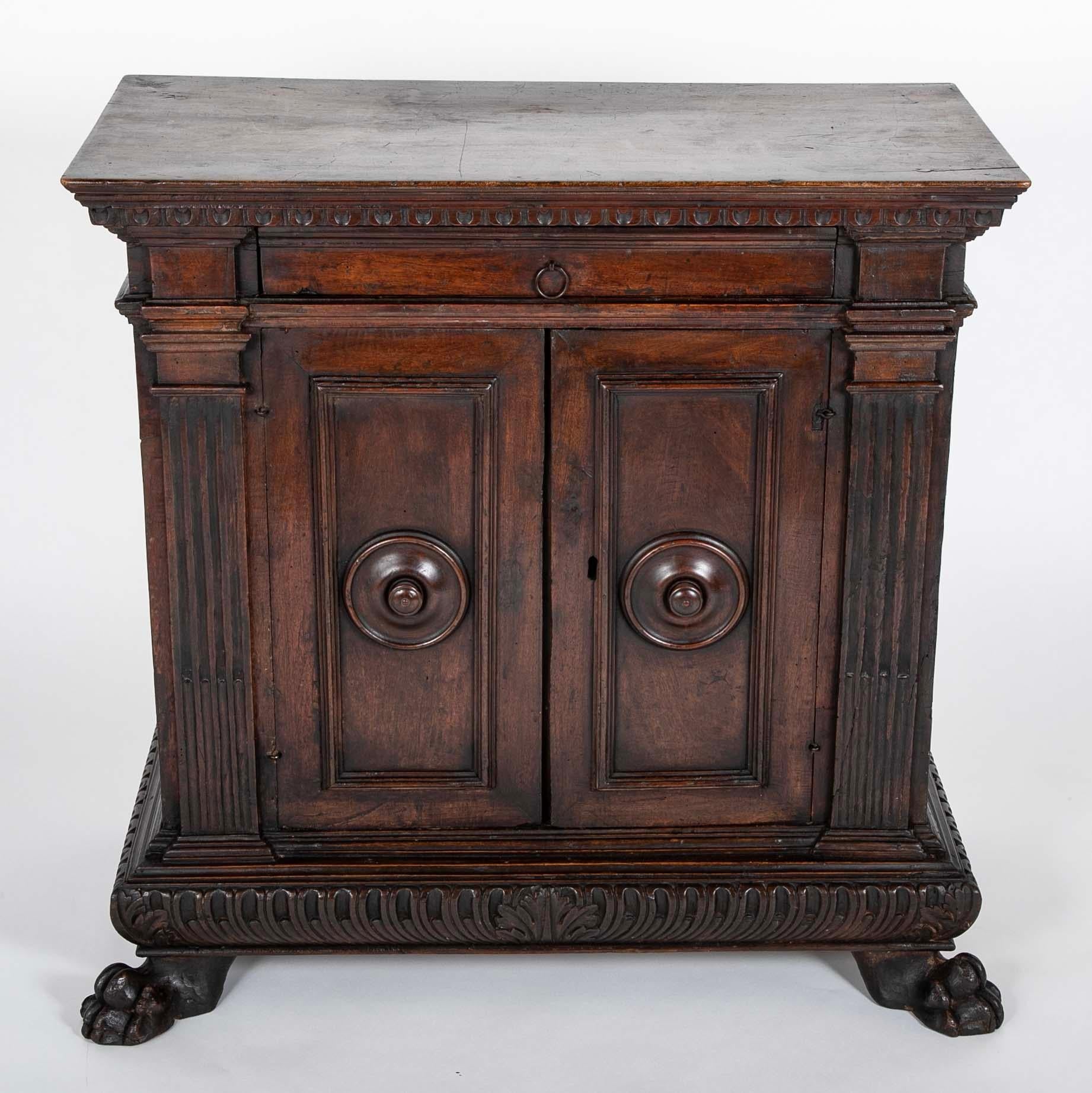 Crédence italienne en noyer du 17e siècle provenant de Toscane. Un seul tiroir au-dessus de deux portes, chacune avec une moulure encadrant un bossage circulaire et un bouton, des colonnes cannelées de chaque côté. La base à godrons est soutenue par