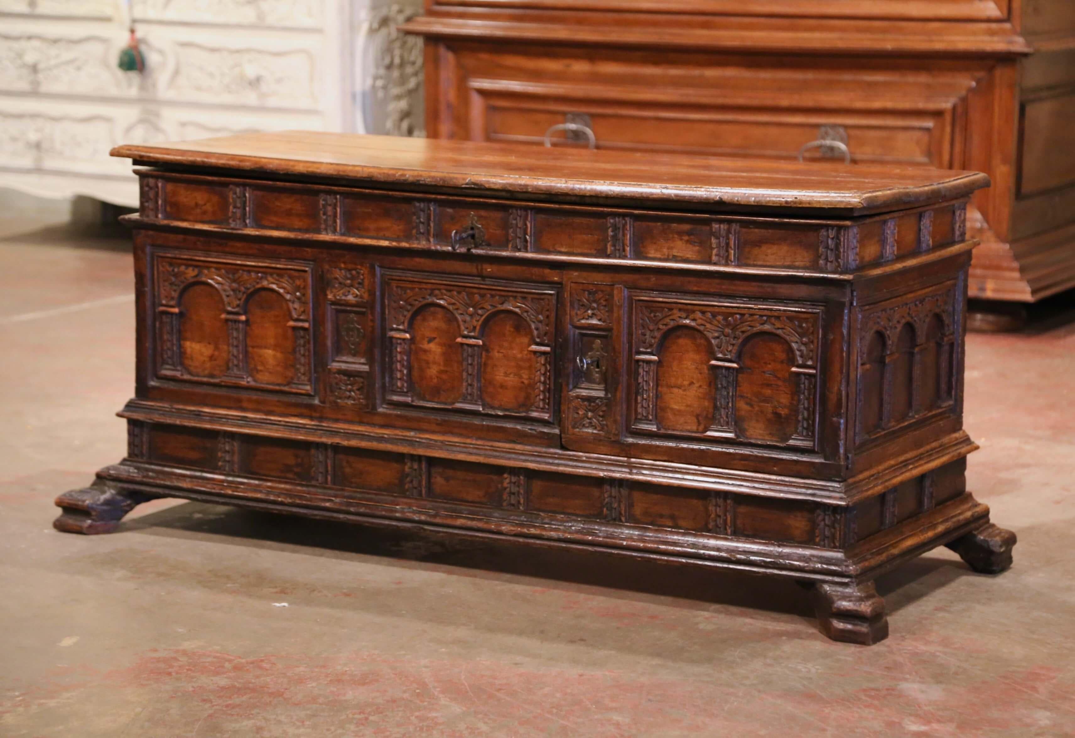 Place this elegant antique coffer at the foot of a king size bed. Crafted in Italy, circa 1680, the rectangular trunk stands on bracket feet. Heavily carved on all three sides with arch and foliage decor, the cabinet features carved panels on the