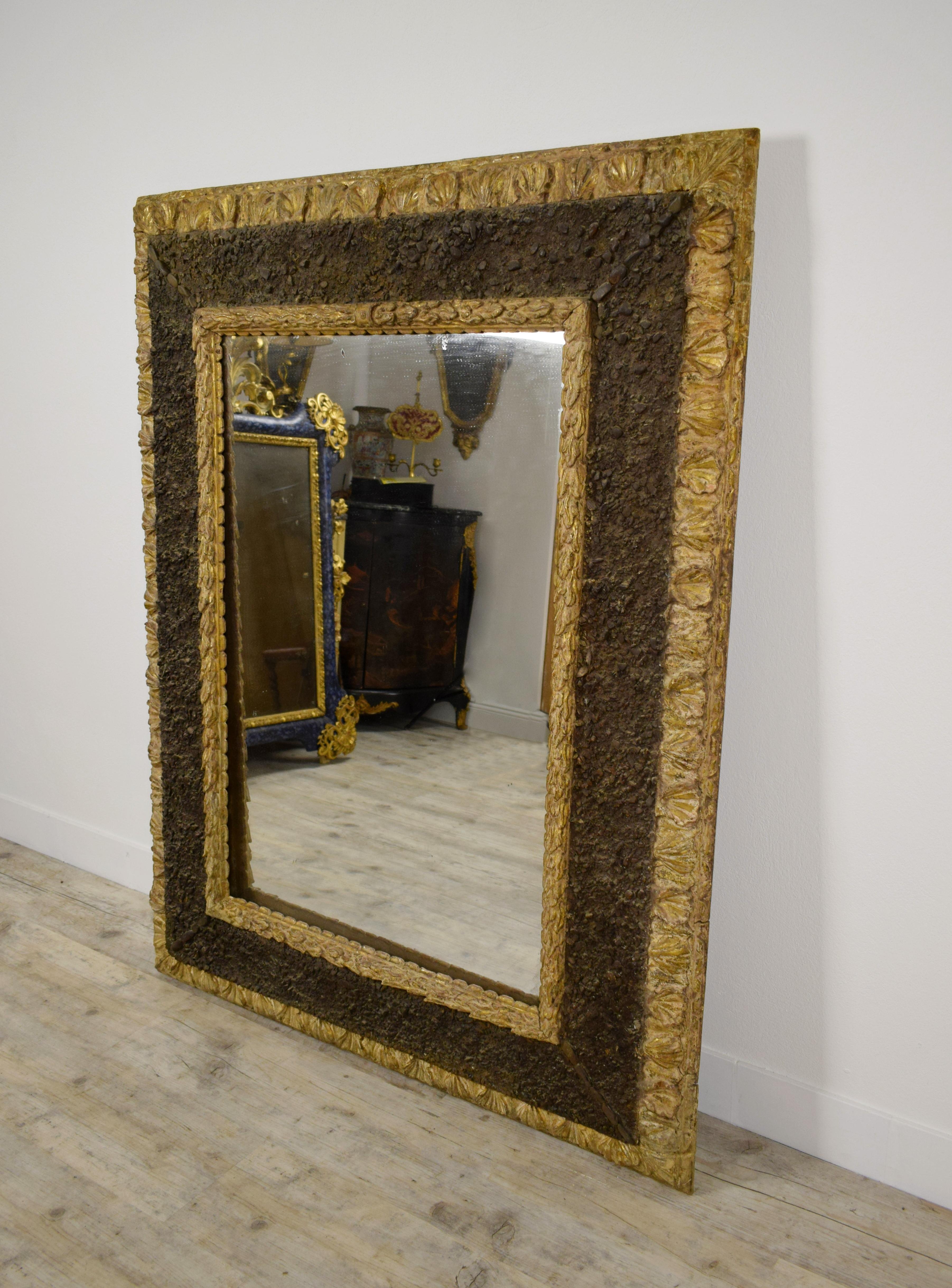 17th century, Italian carved giltwood mirror with small stones

This important mirror, made in Italy in the 17th century, has a rare, if not unique, processing. Rectangular in shape, the wooden frame has three orders of concentric bands. The outer