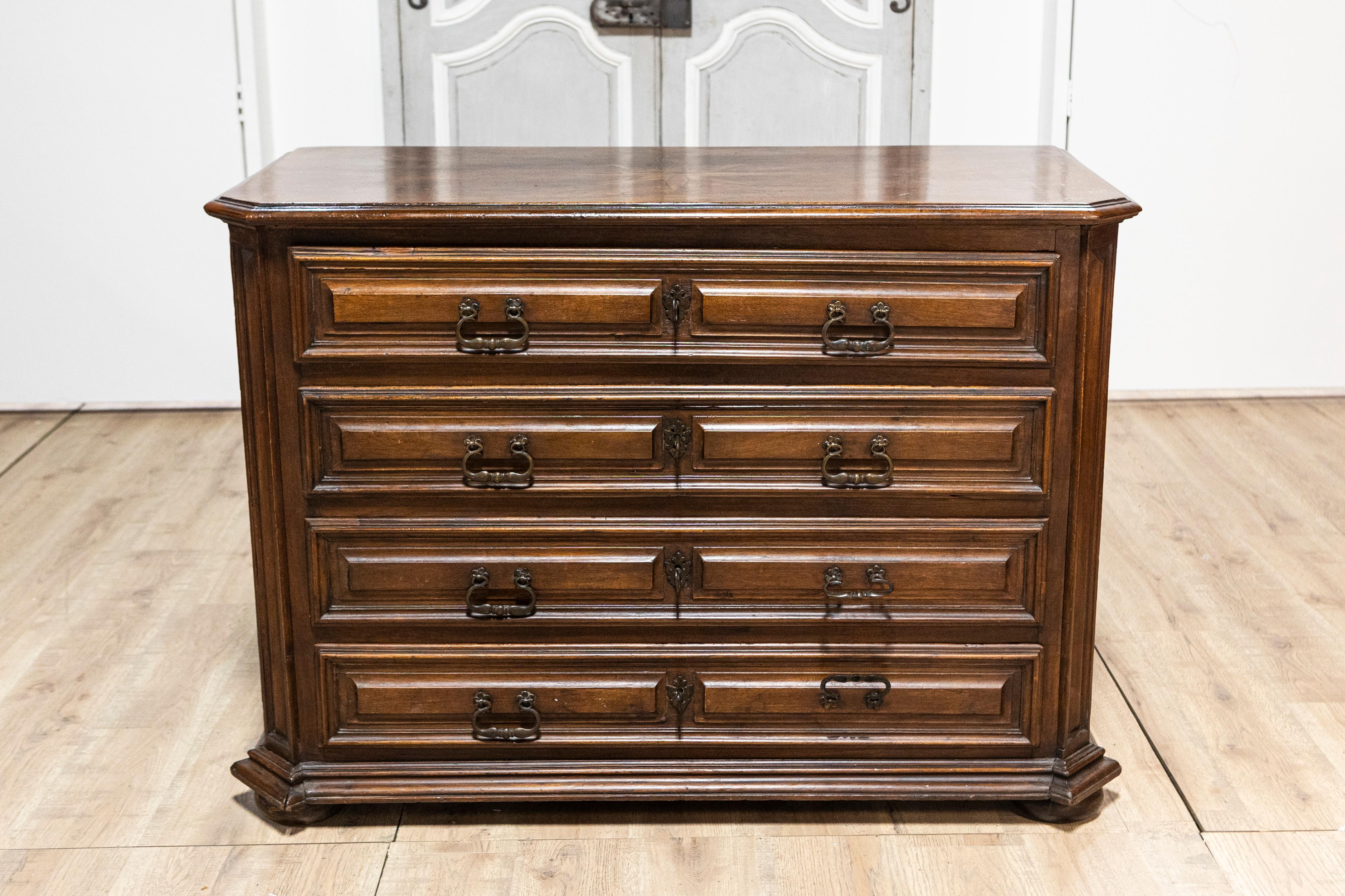 Diese italienische Kommode aus dem 17. Jahrhundert ist ein Beispiel für die Kunstfertigkeit und Eleganz des barocken Möbeldesigns. Die Kommode ist aus reich gemasertem Nussbaumholz gefertigt und verfügt über vier Schubladen, die jeweils mit