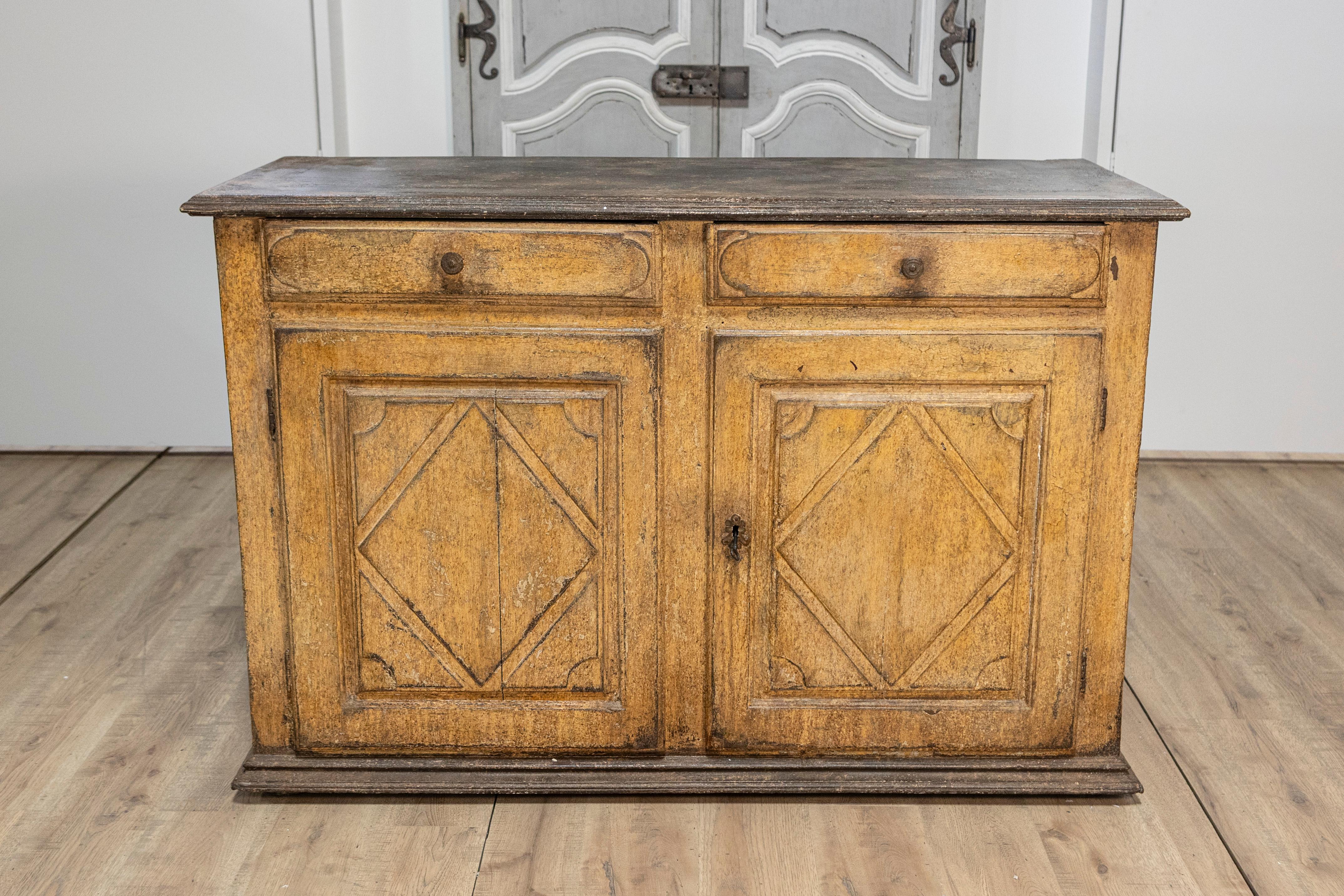 Un buffet italiano dipinto del XVII secolo con motivi a diamante e una patina rovinata. Nato in Italia nel corso del XVII secolo, questo squisito buffet dipinto presenta una finitura giallo antico fortemente degradata e dorata, splendidamente