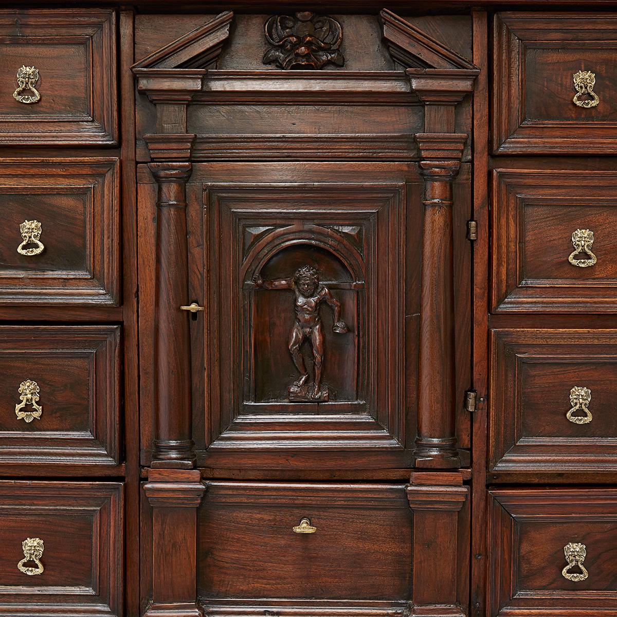 A stunning Genoese carved walnut coin cabinet with twenty-one drawers created to hold secrets from 17th century.  This Italian Louis XIV coin cabinet features an extraordinary  architectural form, the front shows sixteen drawers, two vertical rows