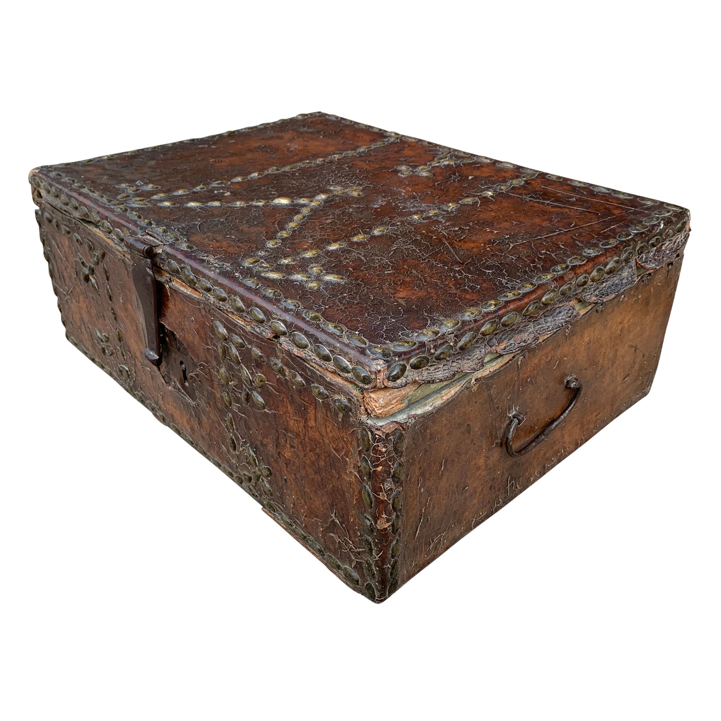 An incredible 17th century Italian leather clad trunk with beautiful well-worn brass nailhead trim in a decorative pattern, with a handwoven indigo dyed linen lining, iron handles, and an iron lock. No key, and trunk does not lock.