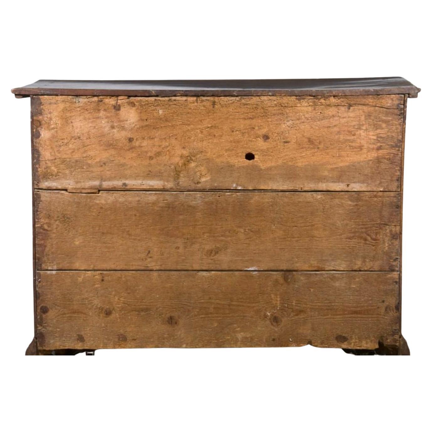 An exquisite 17th century Italian walnut commode with four marquetry inlaid drawers showcasing spectacular and rich inlay work in walnut, made with different precious woods and carved sea shell feet. This exquisite Italian walnut commode from the