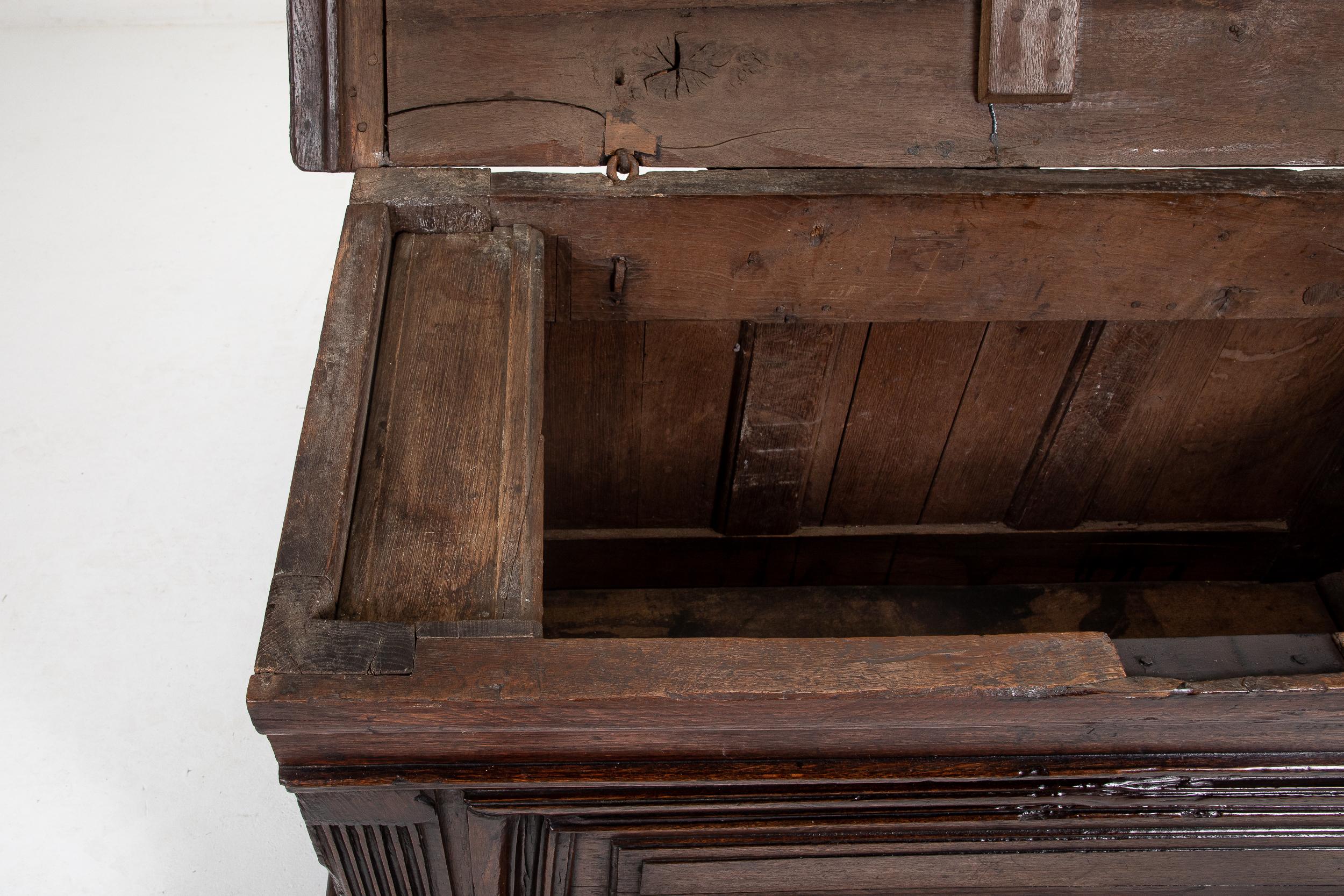 17th Century Italian oak coffer with a boarded top, having a moulded edge, and pin hinges. Having a small hinged compartment on the inside that was used for storing candles. The moulded, panel front is flanked by large stop fluted columns. Raised on