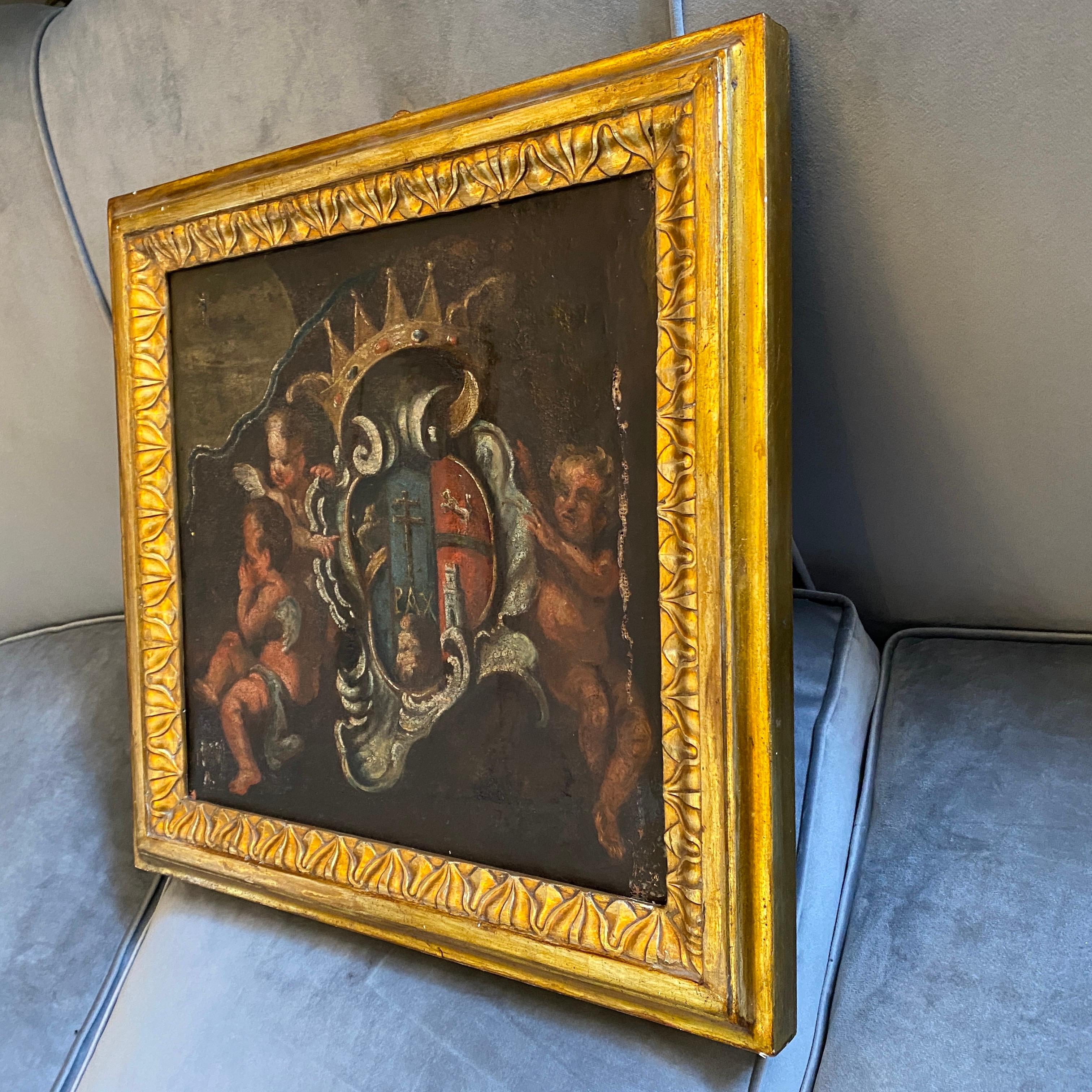A Baroque Italian framed oil on canvas depicting three angels holding a noble coat of arms, the antique gilt wood frame is from the mid-19th century.