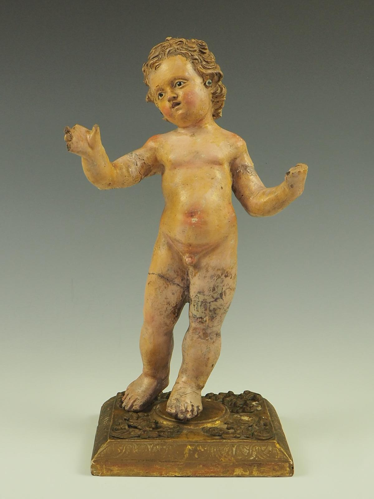 Exquisite product is a polychromed, hand painted terracotta figure that beautifully depicts Baby Jesus. The attention to detail is evident in the figure's glass eyes, which add a lifelike quality to the piece. Standing on a meticulously carved and