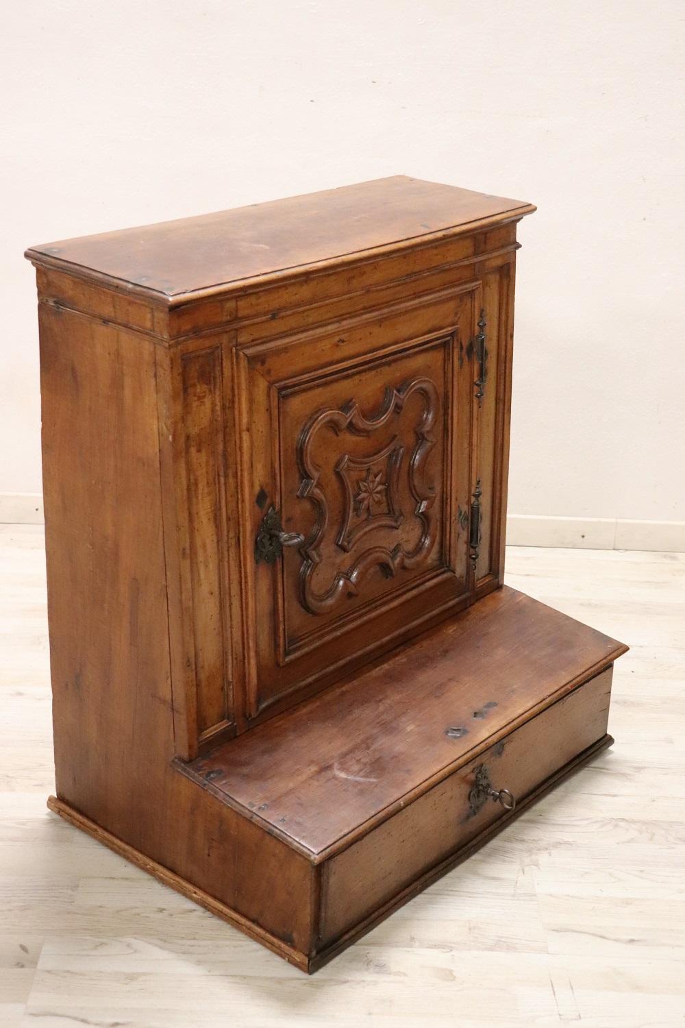 Rare antique Italian kneeler, Mid-17th Century Louis XIV. Made of solid walnut with relief decoration carved into the wood. In the part dedicated to the knees there is a compartment. Of great value all the hand forged iron part of the escutcheons