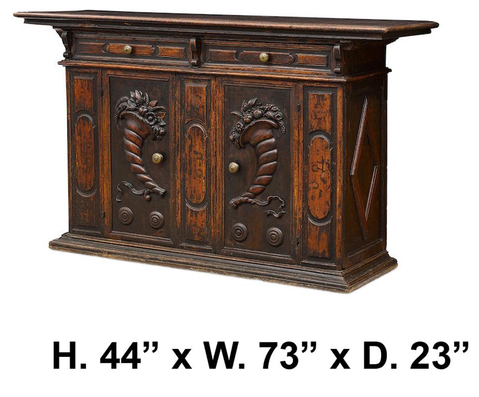Outstanding 17th century Italian Renaissance carved walnut credenza. The wooden top above frieze sustaining two drawers each centred by typical baluster bronze handles, all-over two doors carved with unusual floral and cornucopia motif. 

Bearing