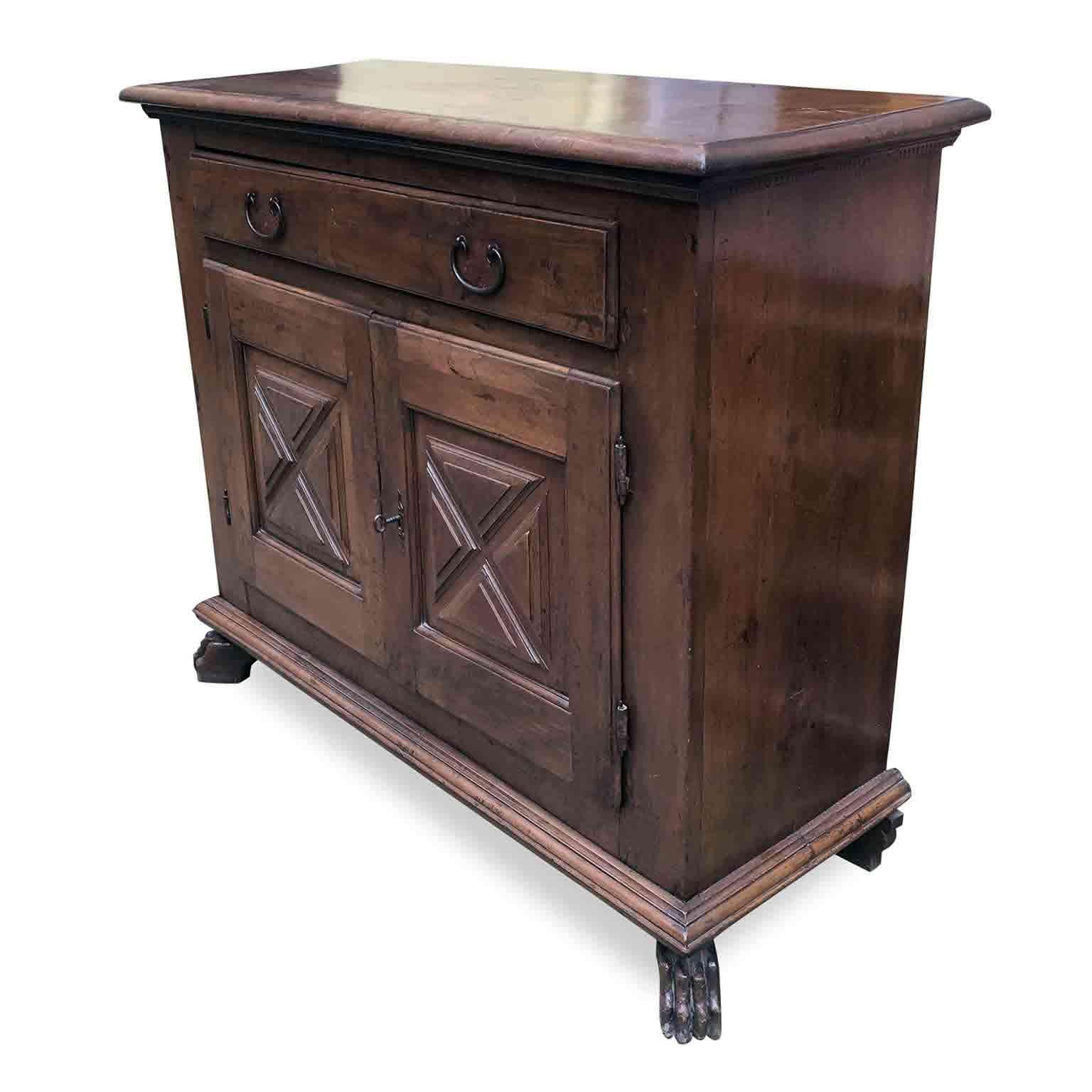From Italy an antique solid walnut two-door sideboard dating back to 17th century, it is a Baroque Italian taste hand carved walnut credenza or buffet coming from a private collection in Milan, in good age related condition with a beautiful warm