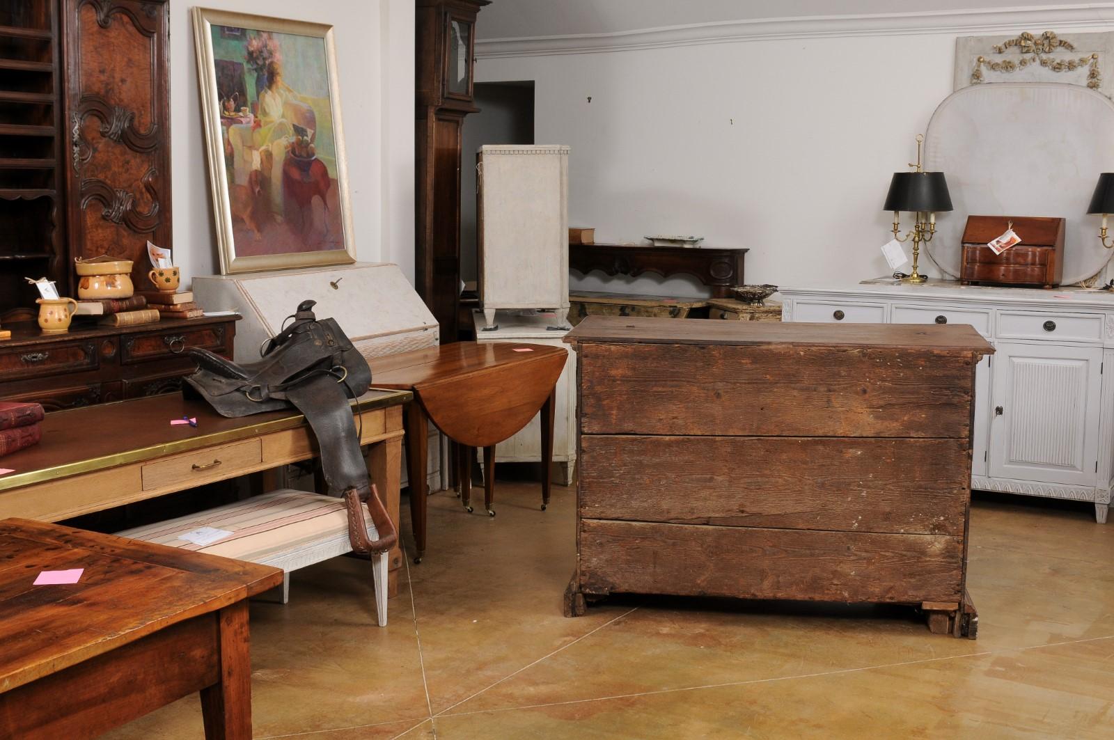 An Italian walnut commode from the 17th century, with drop front desk and three large drawers. Created in Italy during the 17th century, this commode features a rectangular top with partial lift top, sitting above a drop front desk concealed behind
