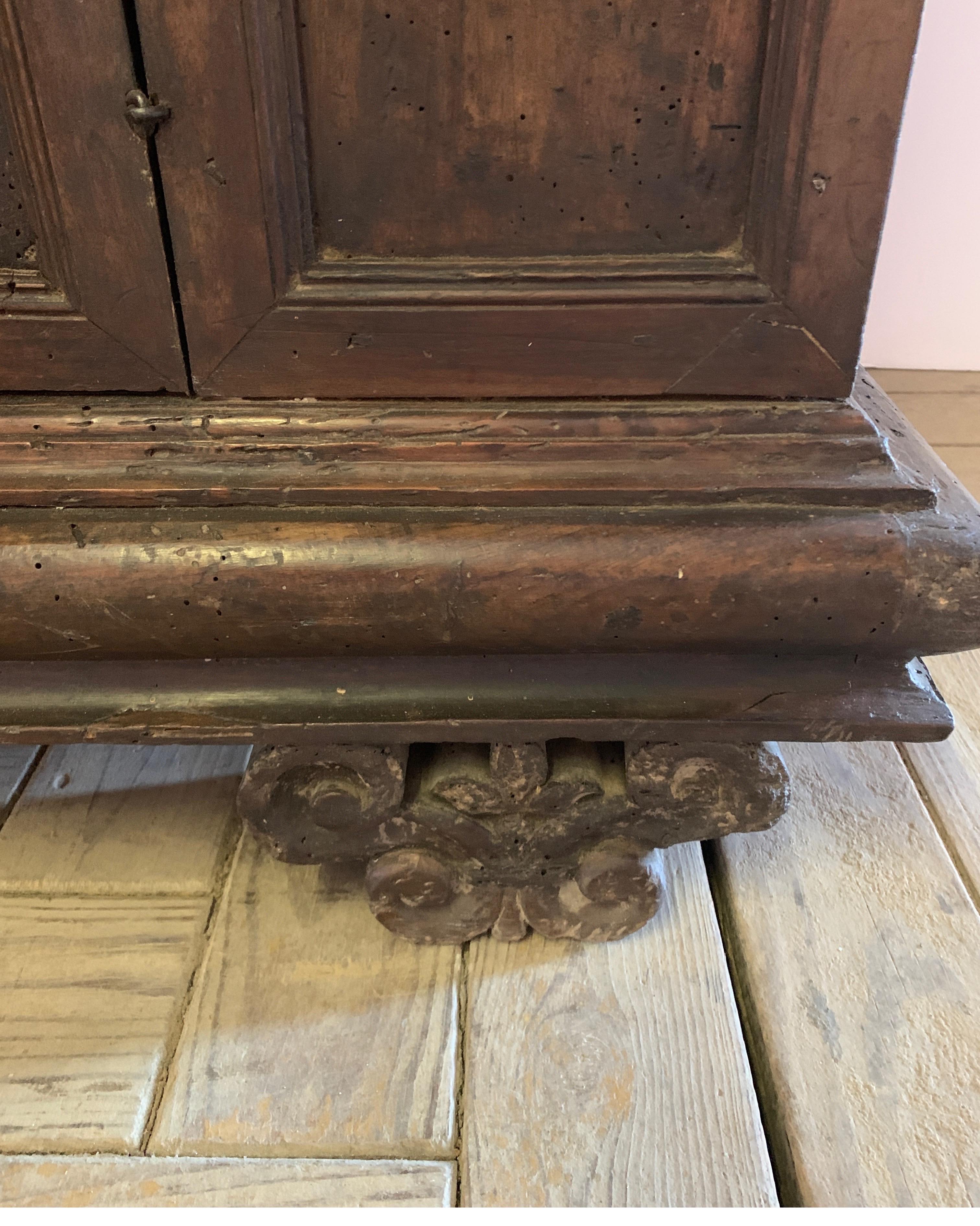 Early Tuscan buffet with three doors, middle shelf for lots of storage. It has beautifully carved feet but otherwise simple and modern shape in walnut wood. It has 3 key for the locks as well. Prior bug holes shown in photos.