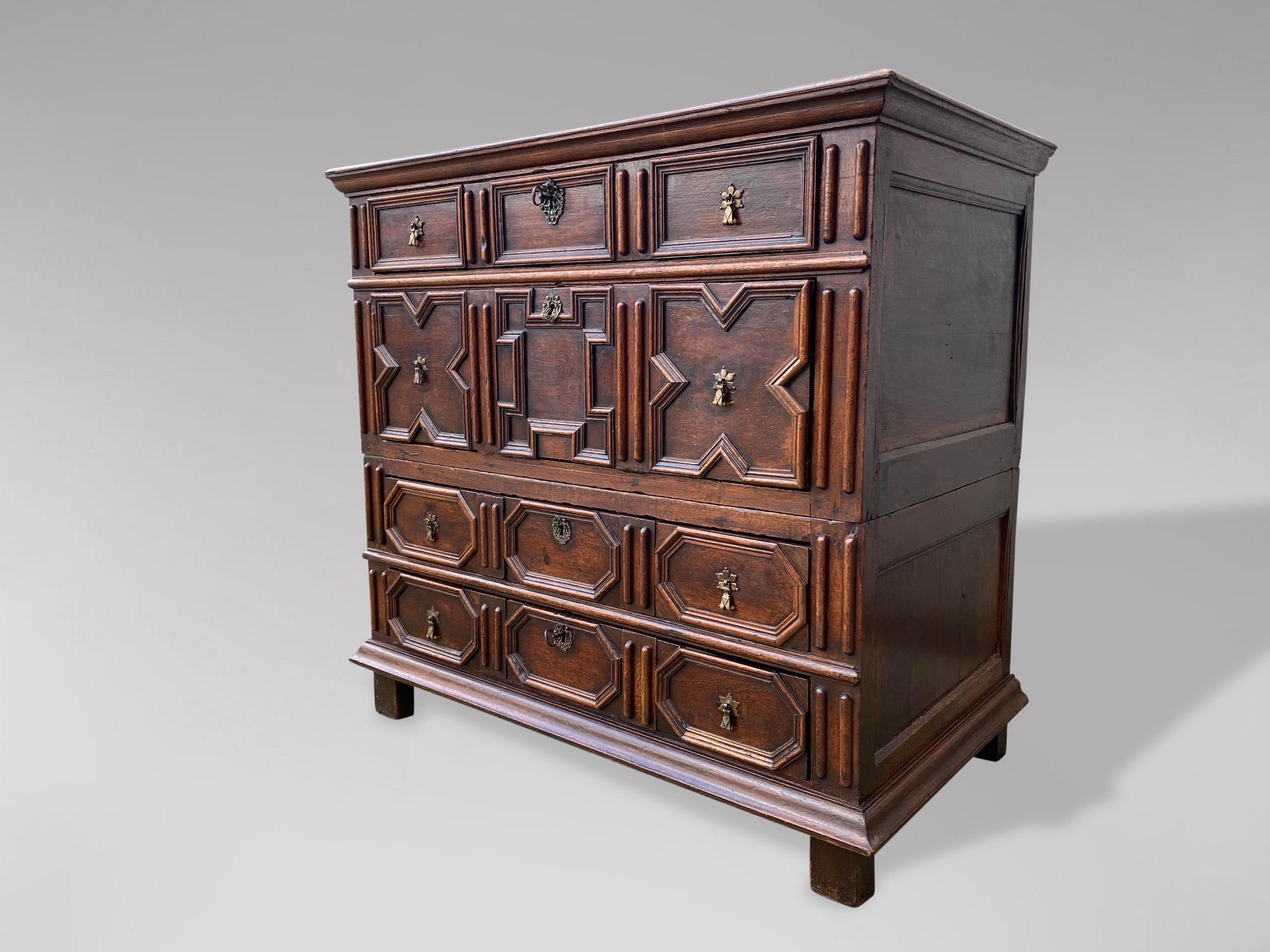 A 17th century, Charles II, Jacobean oak geometric chest of drawers. Rectangular planked top with moulded edge above four long graduated oak lined geometric moulded drawers with the original brass drop handles, escutcheons and locks, raised on the
