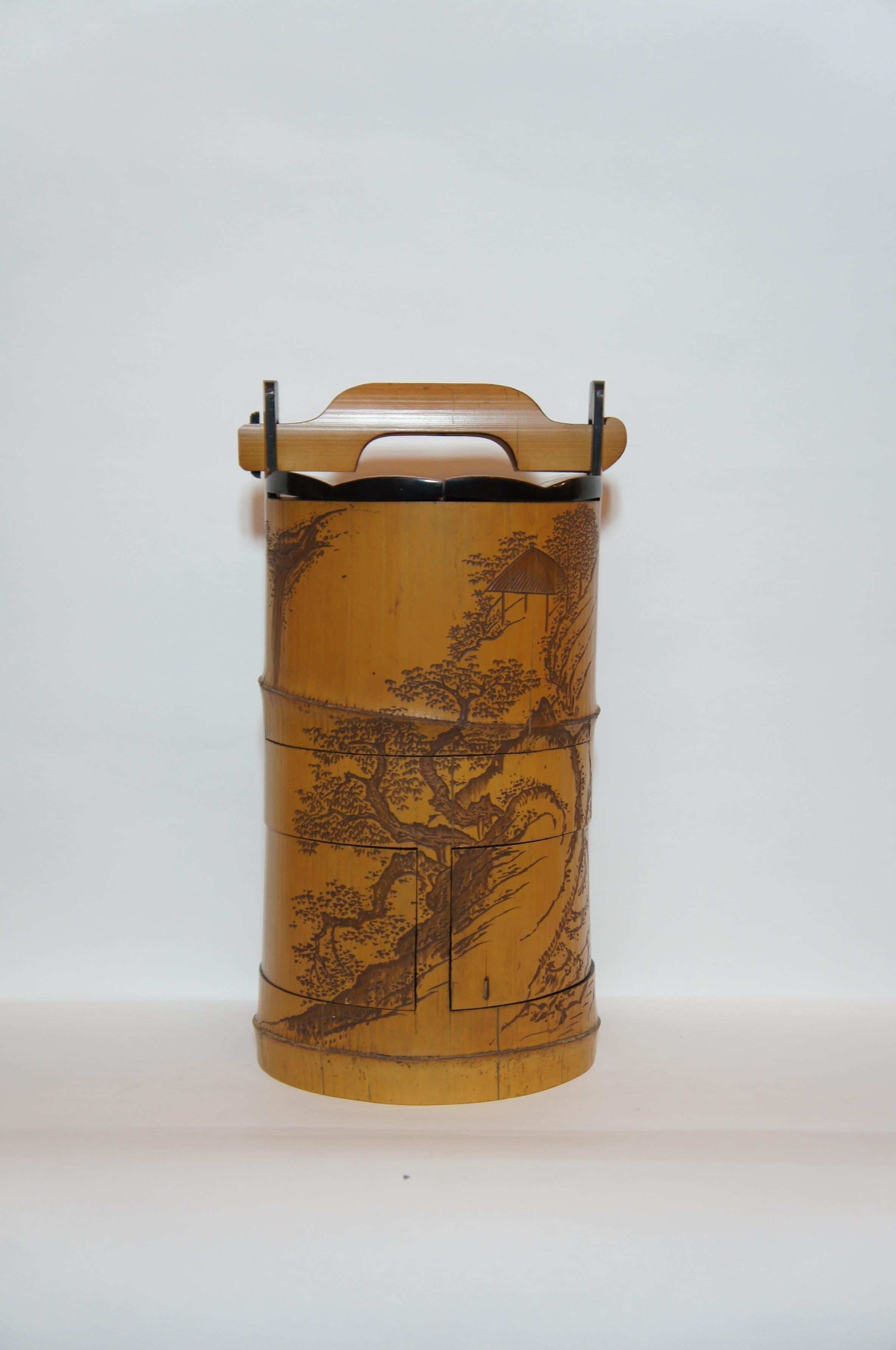 This is an antique Japanese bento box from Edo era which was used for cherry blossom viewing party. It is made with bamboo and painted with Japanese lacquer. Landscapes with water falls and some pine trees are carved into the surface.