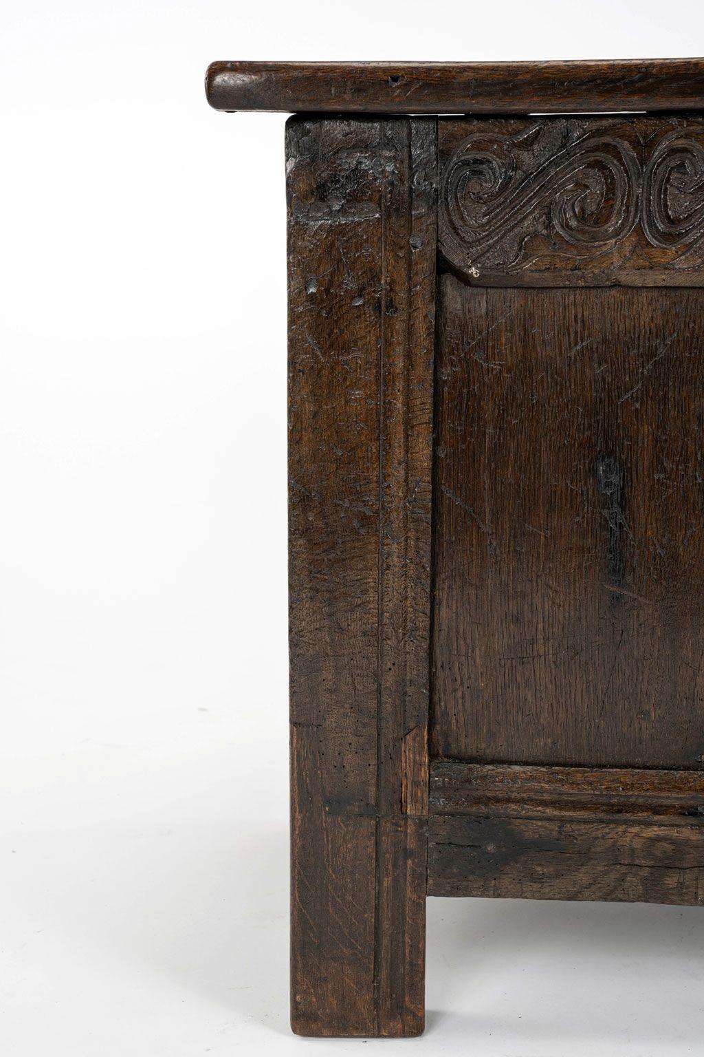17th century joined oak triple panel top coffer with hinged triple panel top. Hand-carved decoration adorns front rail and front. Suitable to function as a table or seat, as well as for storage. Perfect to place at the foot of a bed or sitting under