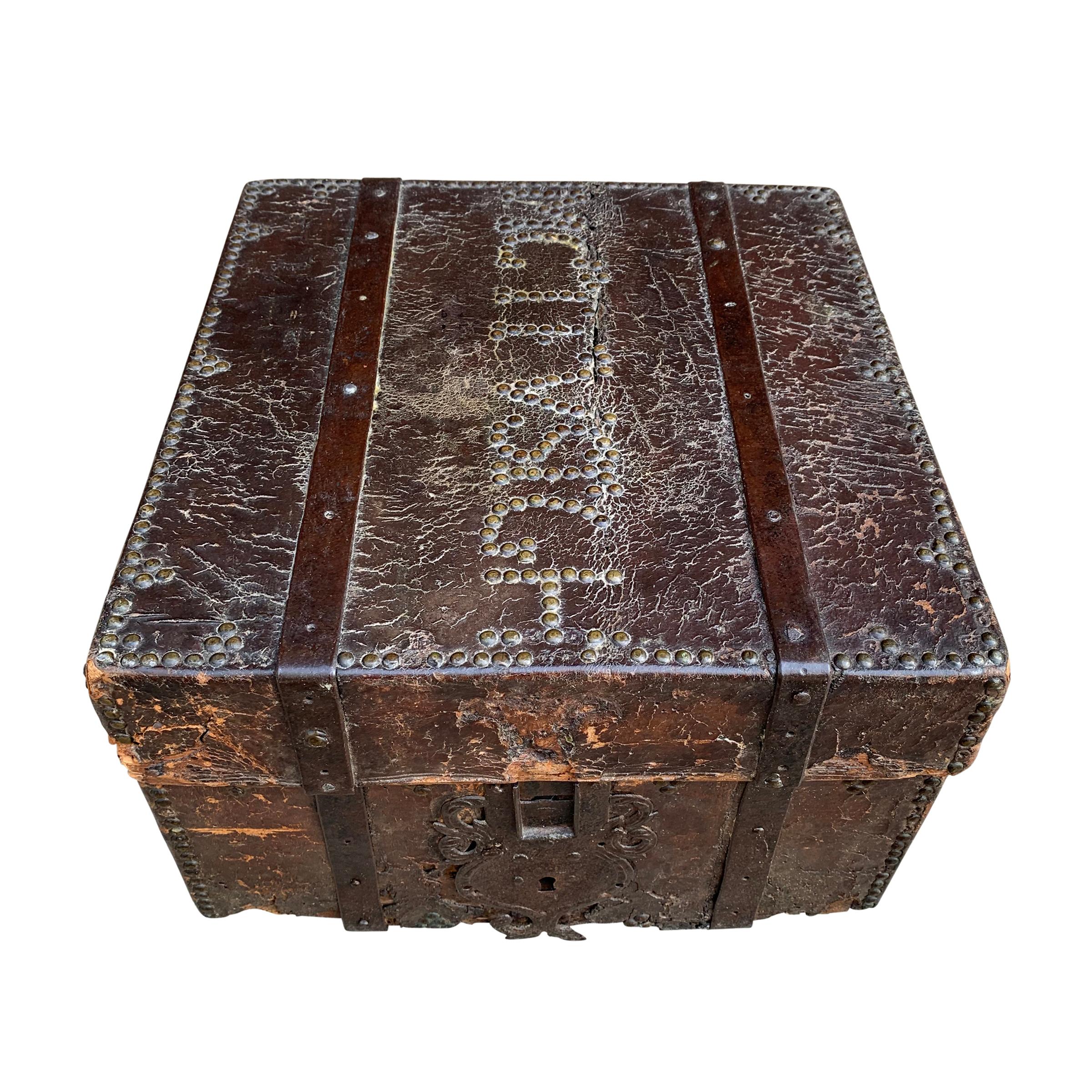 A stunning 17th century Italian leather covered wood trunk covered in brass nail heads, some spelling out a word on top, and with iron strap hinges and handles, and with a divided interior with a striped hand-painted paper liner.